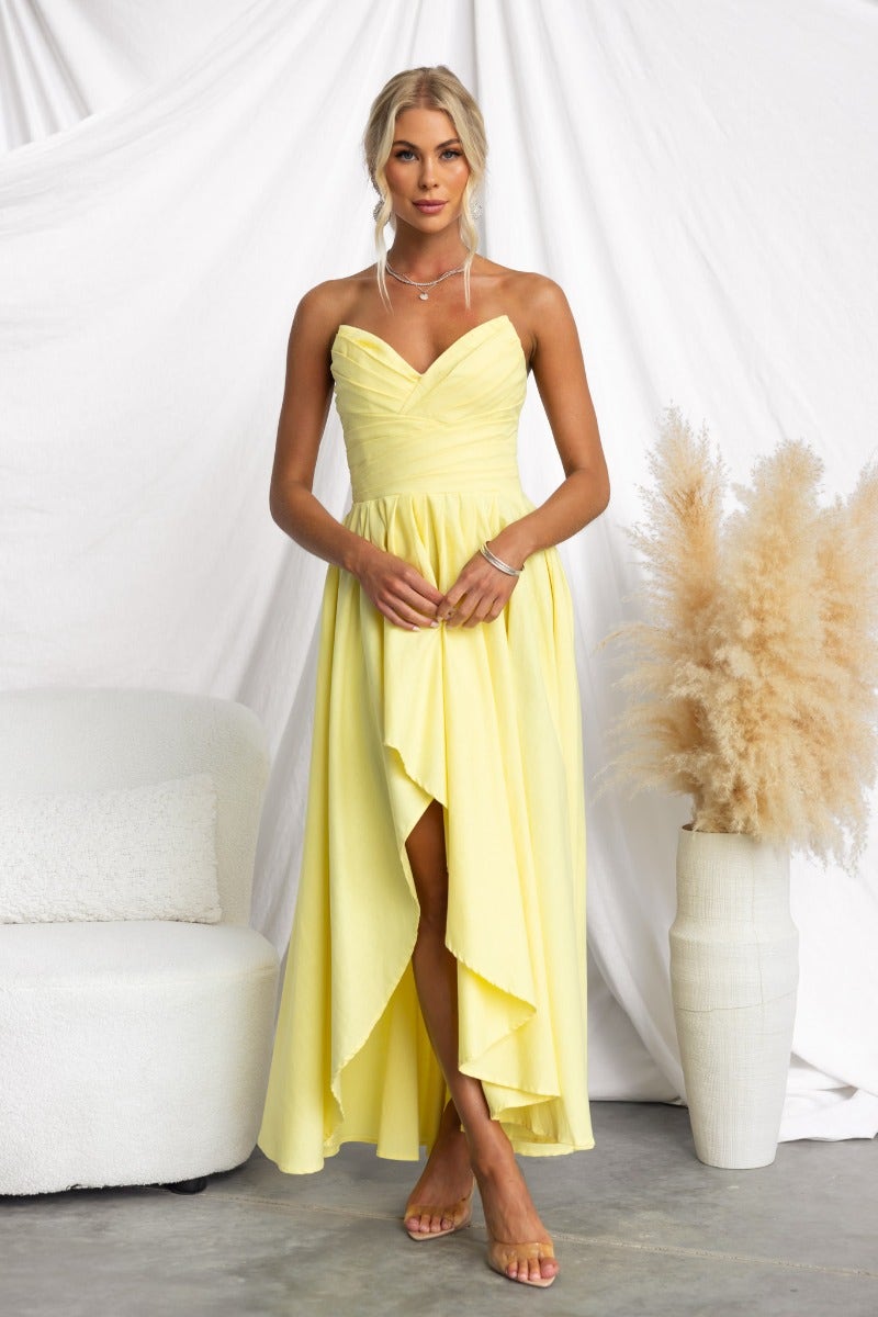 Strapless yellow Kiss And Tell Maxi Dress with asymmetric hem, styled for a fresh summer look.