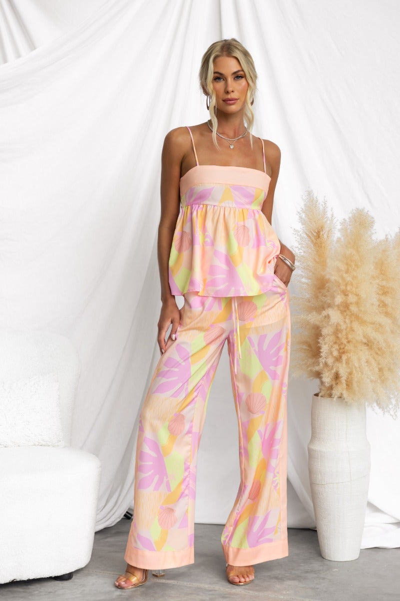 Woman in Ibiza Pants with abstract pastel print, mid-high waist, and elastic waistband, styled with a matching top.
