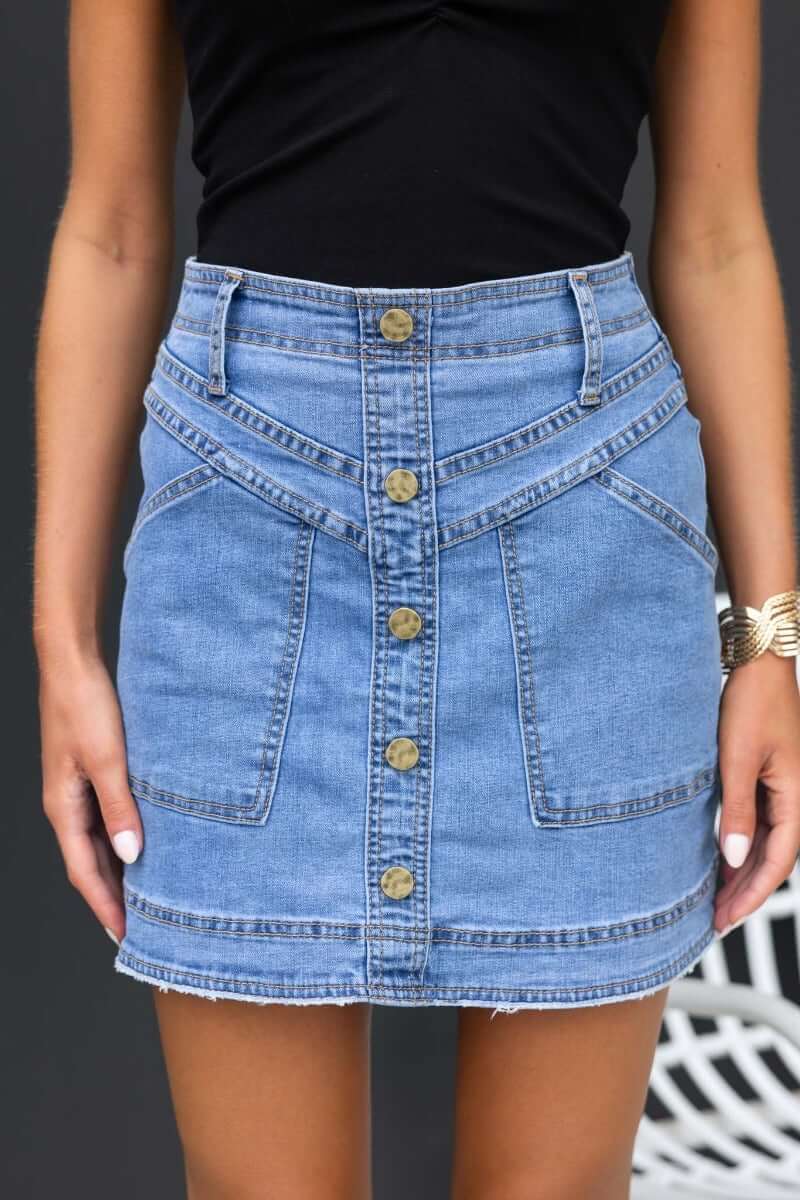 Roy Denim Skirt featuring mid-high waist, faux buttons, front pockets, and distressed hem in structured denim.
