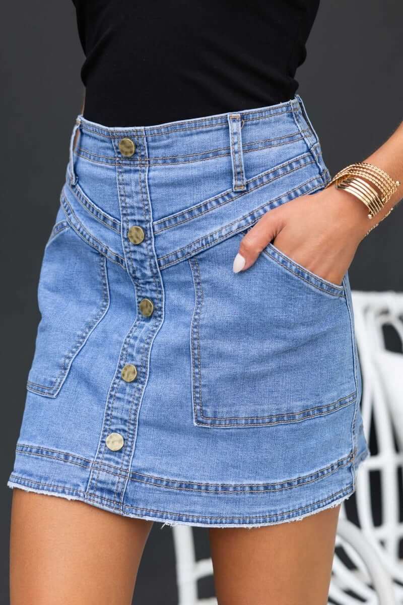 Roy Denim Skirt featuring a mid-high waist, faux buttons, front pockets, and a distressed hem for a stylish look.