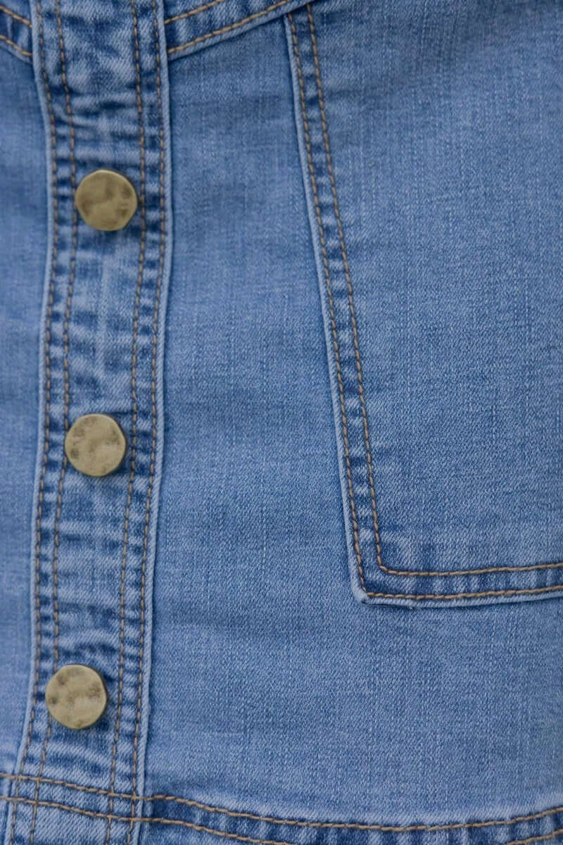 Close-up of Roy Denim Skirt showcasing faux buttons and front pocket detail in structured denim.