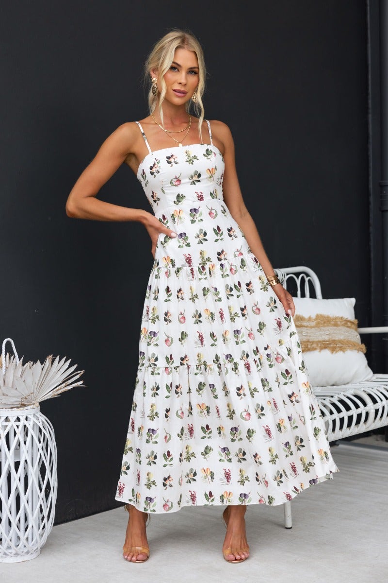 Carlyle Maxi Dress in white floral print, featuring adjustable straps and a flowing silhouette, perfect for warm weather styling.