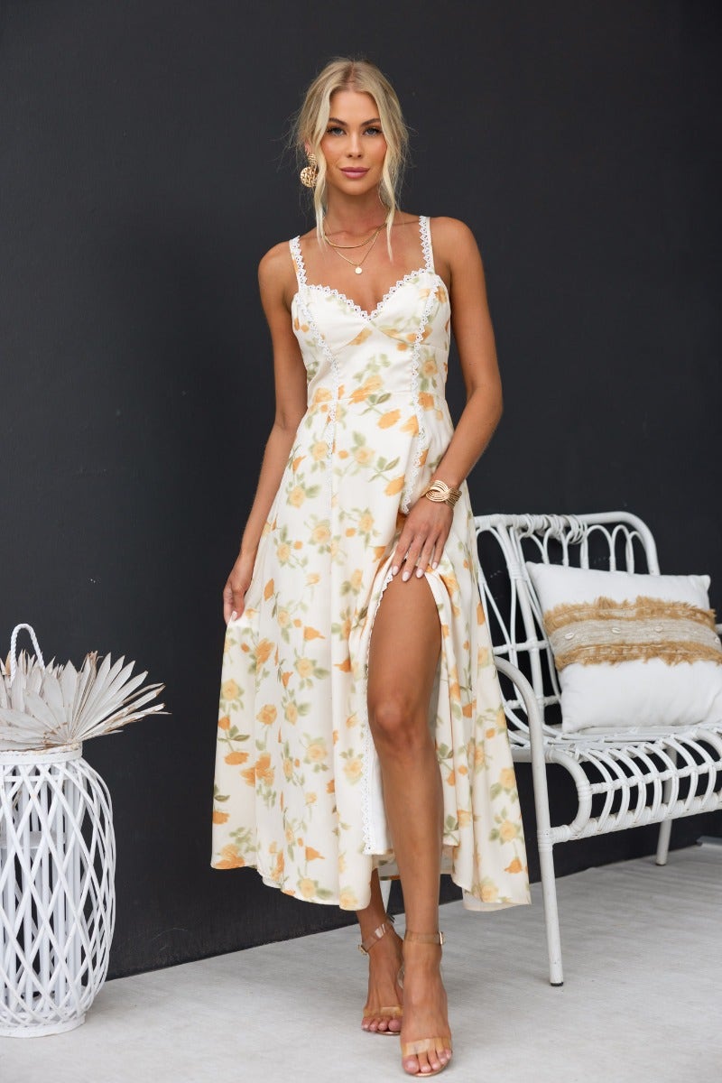 Model wearing a floral print Brigita midi dress with adjustable straps, lace detailing, and a front split.