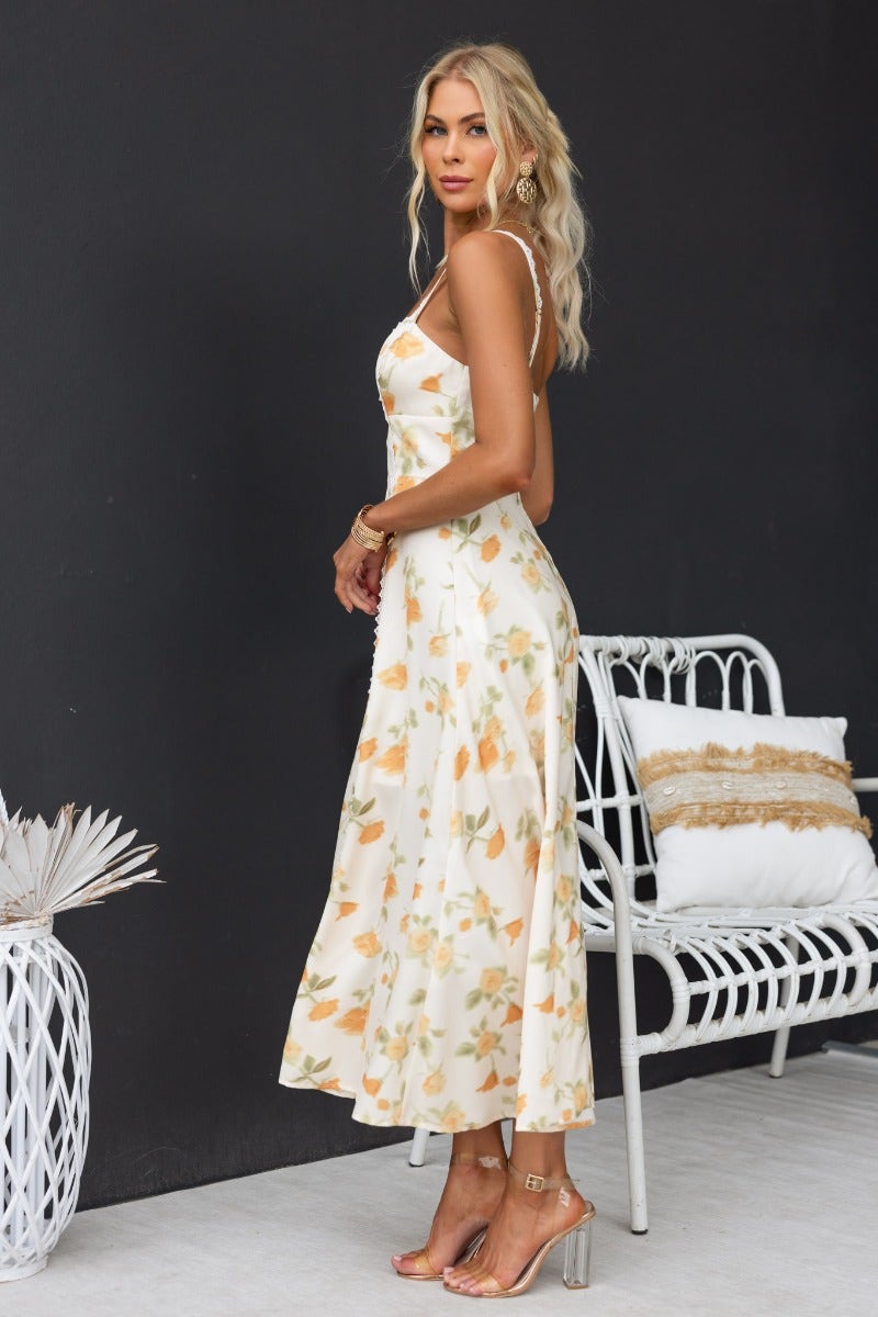 Model showcases Brigita Midi Dress, a floral print dress with adjustable straps and lace detailing.