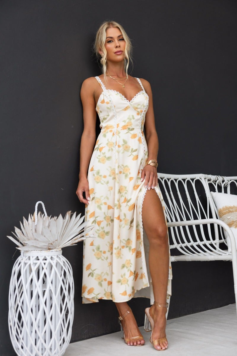 Brigita Midi Dress featuring a floral print, adjustable straps, and lace detailing, styled with a front split.