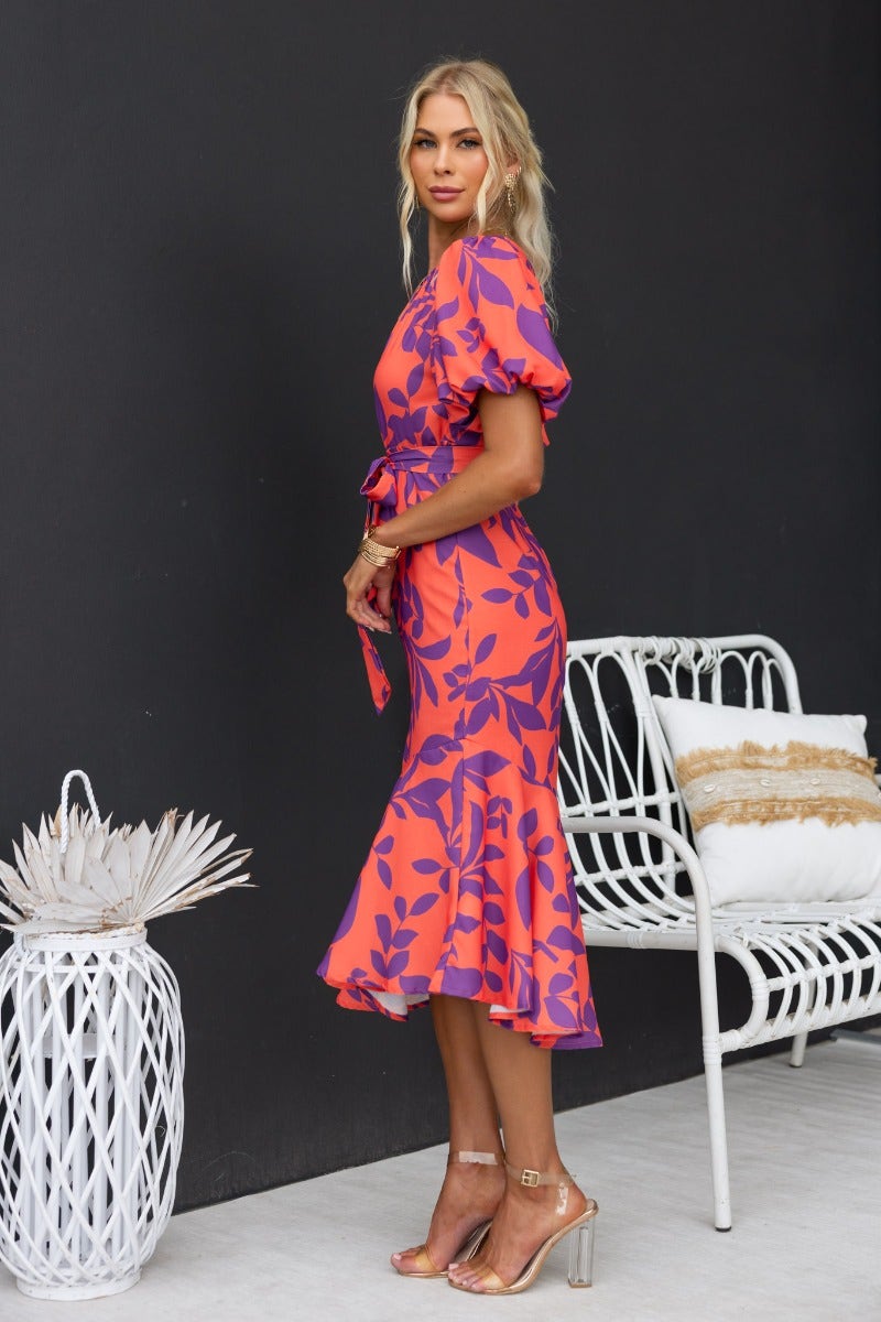 Side view of a model wearing a floral print Linus Midi Dress with puff sleeves and a tie waist.