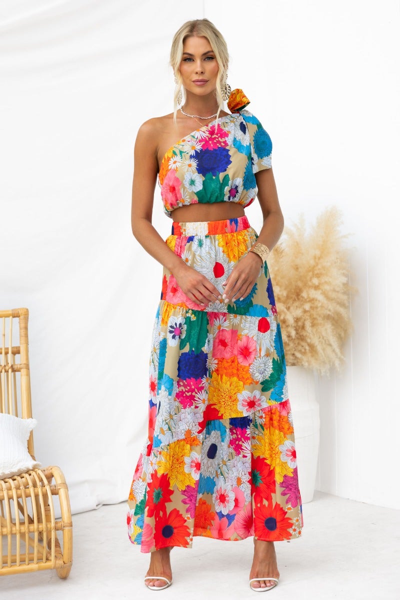 Model wearing a floral print Good Luck Charm maxi skirt with a matching crop top, posing in a bright, airy setting.