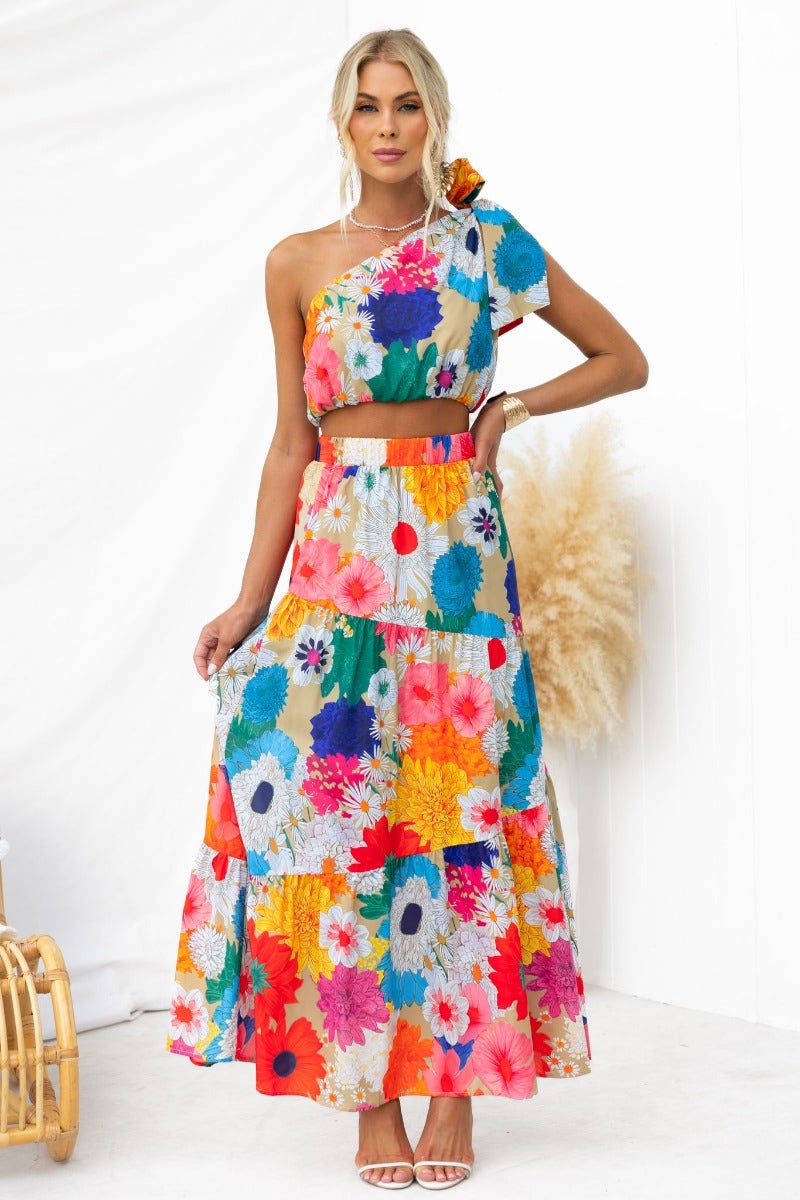 Colorful floral print maxi skirt with matching top, featuring a one-shoulder design and an elastic waistband.