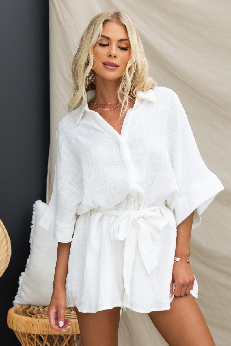 Model wearing a white Rowson Playsuit with a collar, button-up front, and removable tie for an oversized fit.