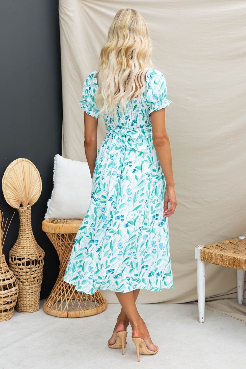Model wearing the Teava Midi Dress featuring a floral print, sweetheart neckline, and back tie.