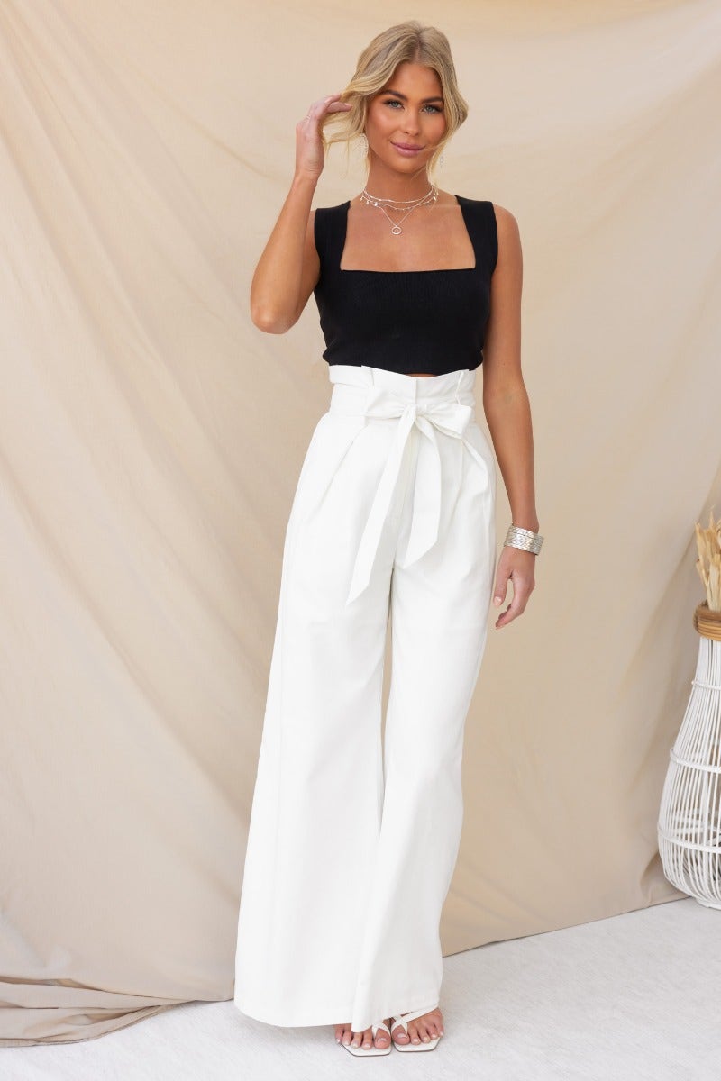 Model wearing black ribbed knit Carrie Top with square neckline, paired with wide-leg white pants and stylish accessories.