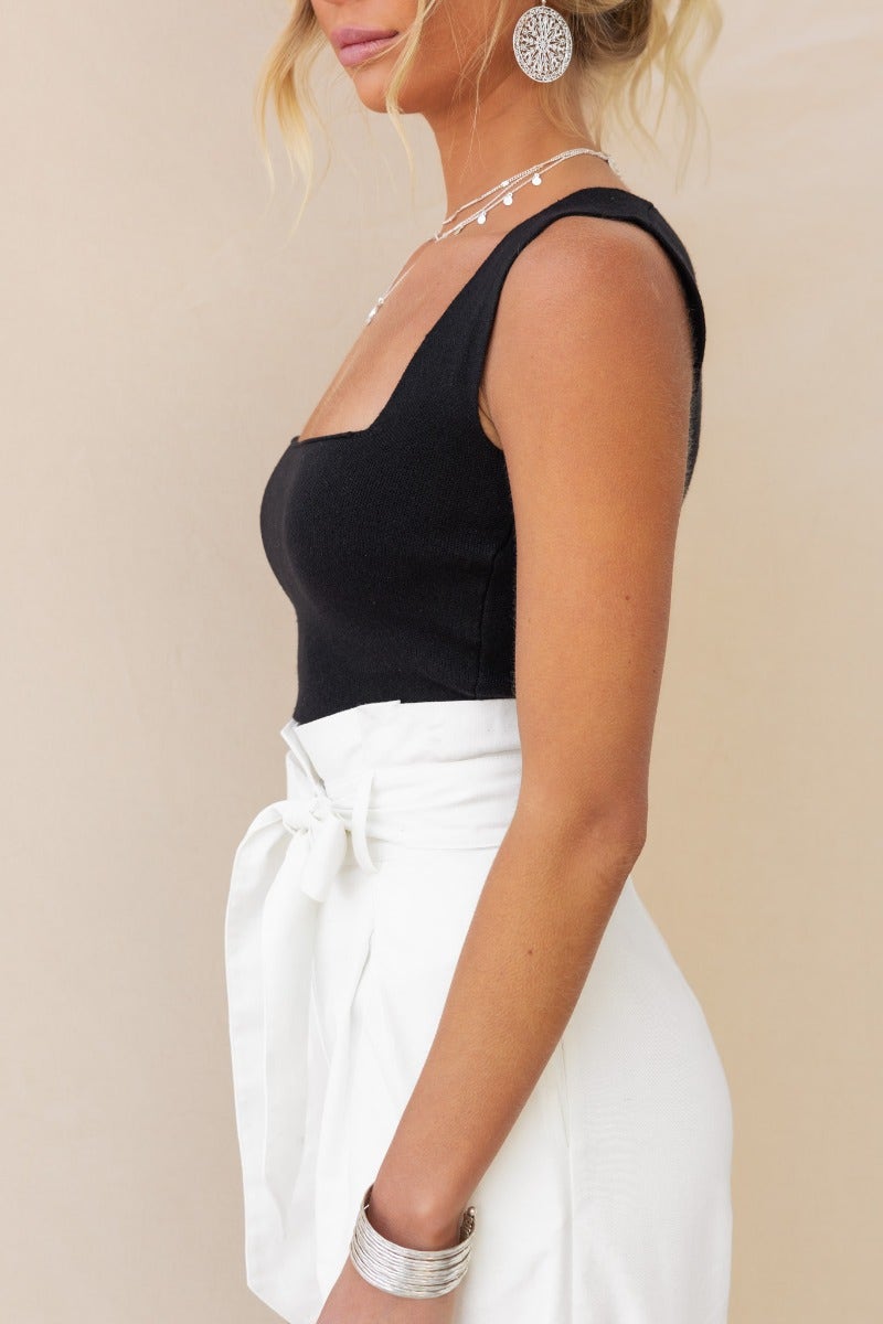 Carrie Top in black ribbed knit with square neckline, paired with high-waisted white shorts for a stylish look.