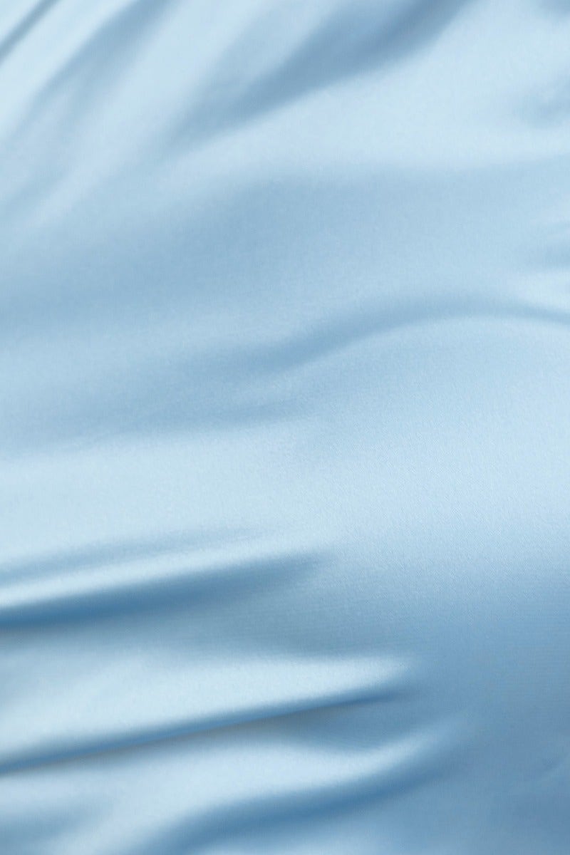 Close-up of blue satin fabric, showcasing smooth texture and sheen, perfect for stylish apparel like the Vella Top.