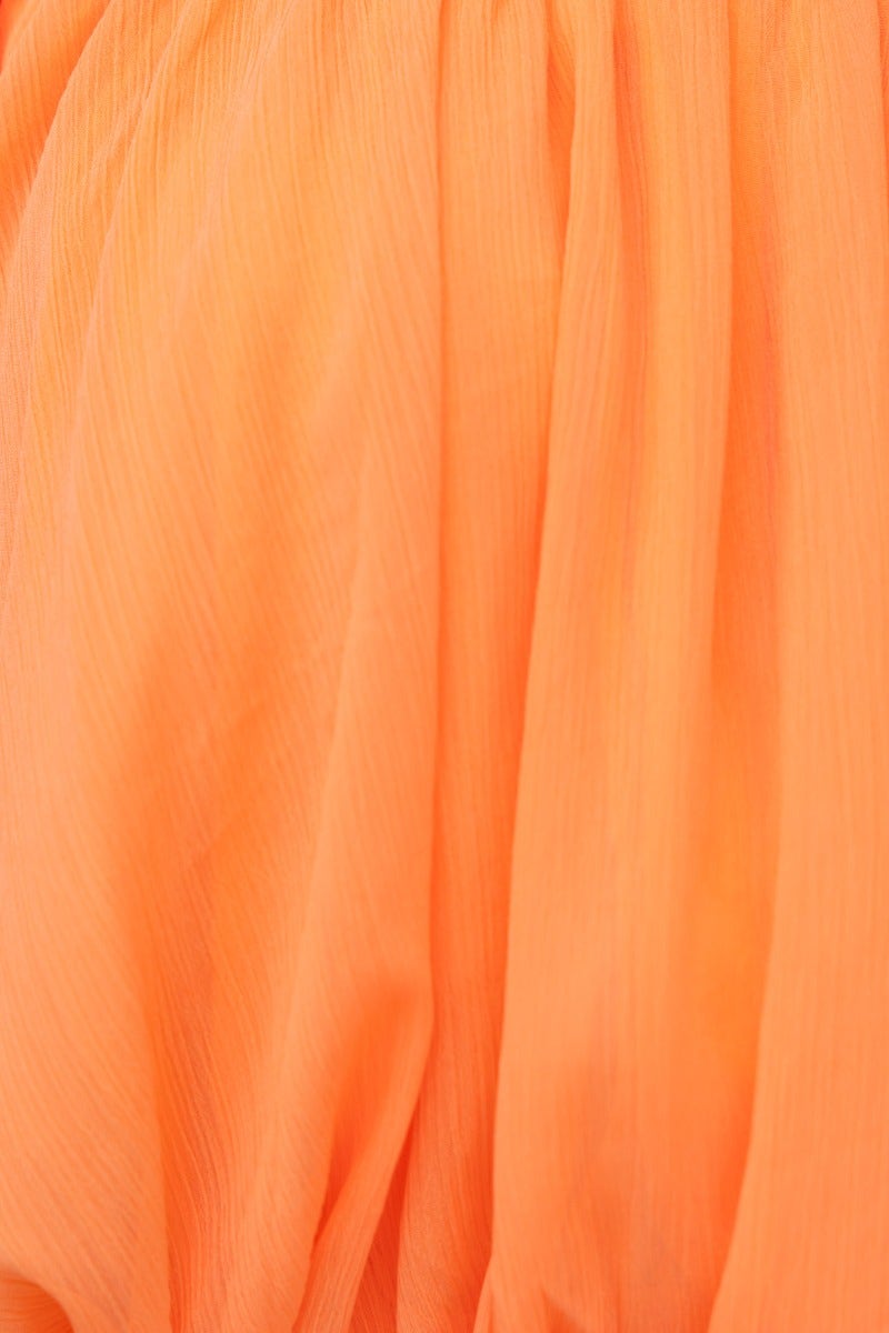 Close-up of lightweight orange chiffon fabric, showcasing soft texture and vibrant color.