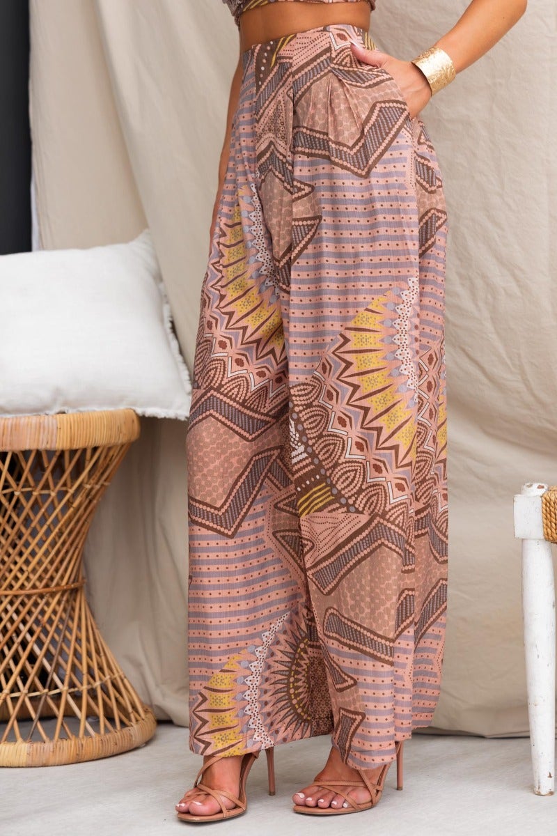 Halia Pants featuring an abstract print, mid-high waist, and pockets, styled for a chic summer look.