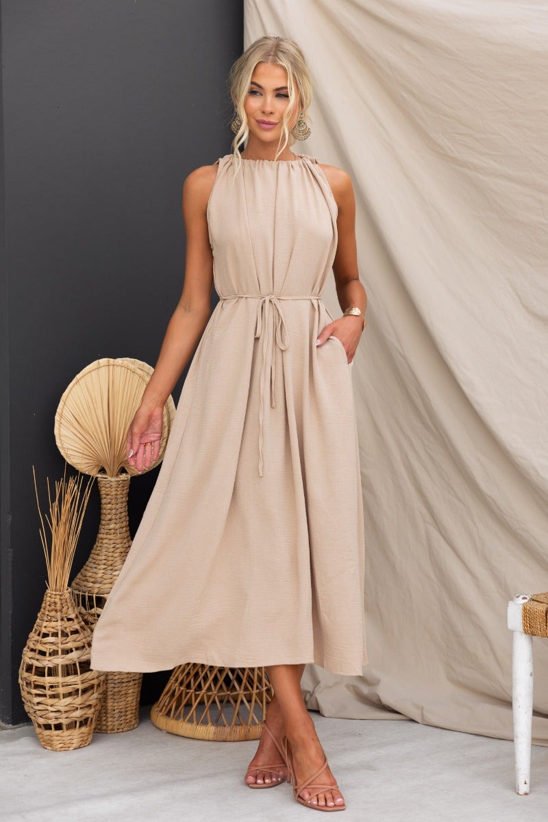 Model wearing Iwaki Maxi Dress with adjustable tie neckline and pockets, set against a neutral backdrop.