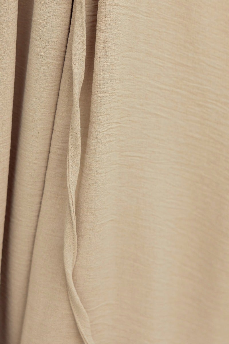 Close-up of lightly textured beige fabric of the Iwaki Maxi Dress, showcasing its soft, stretchy material.