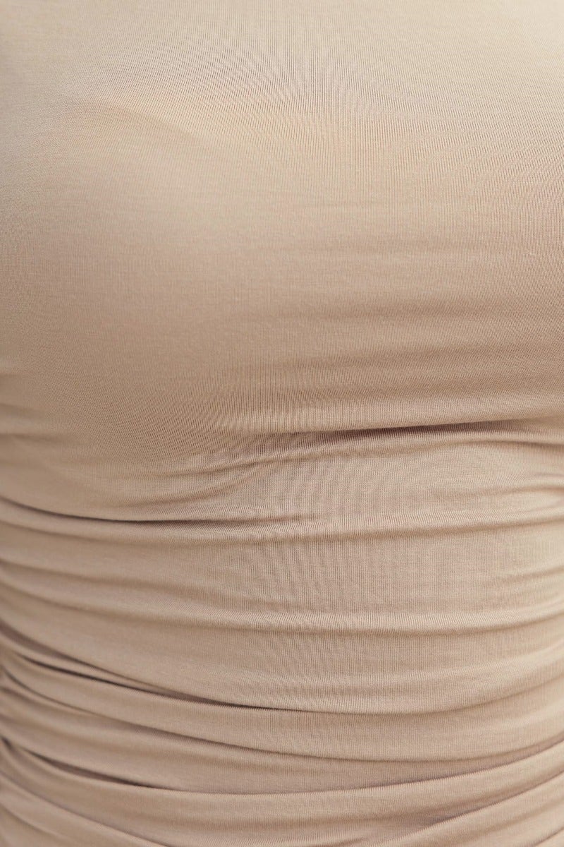 Close-up of a beige cotton blend top with ruched details and a smooth texture, highlighting its stretch and fit.