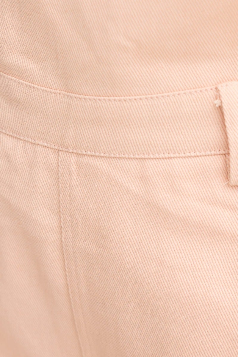 Close-up of the waistband of nude short overalls, showcasing structured fabric and stitching detail.
