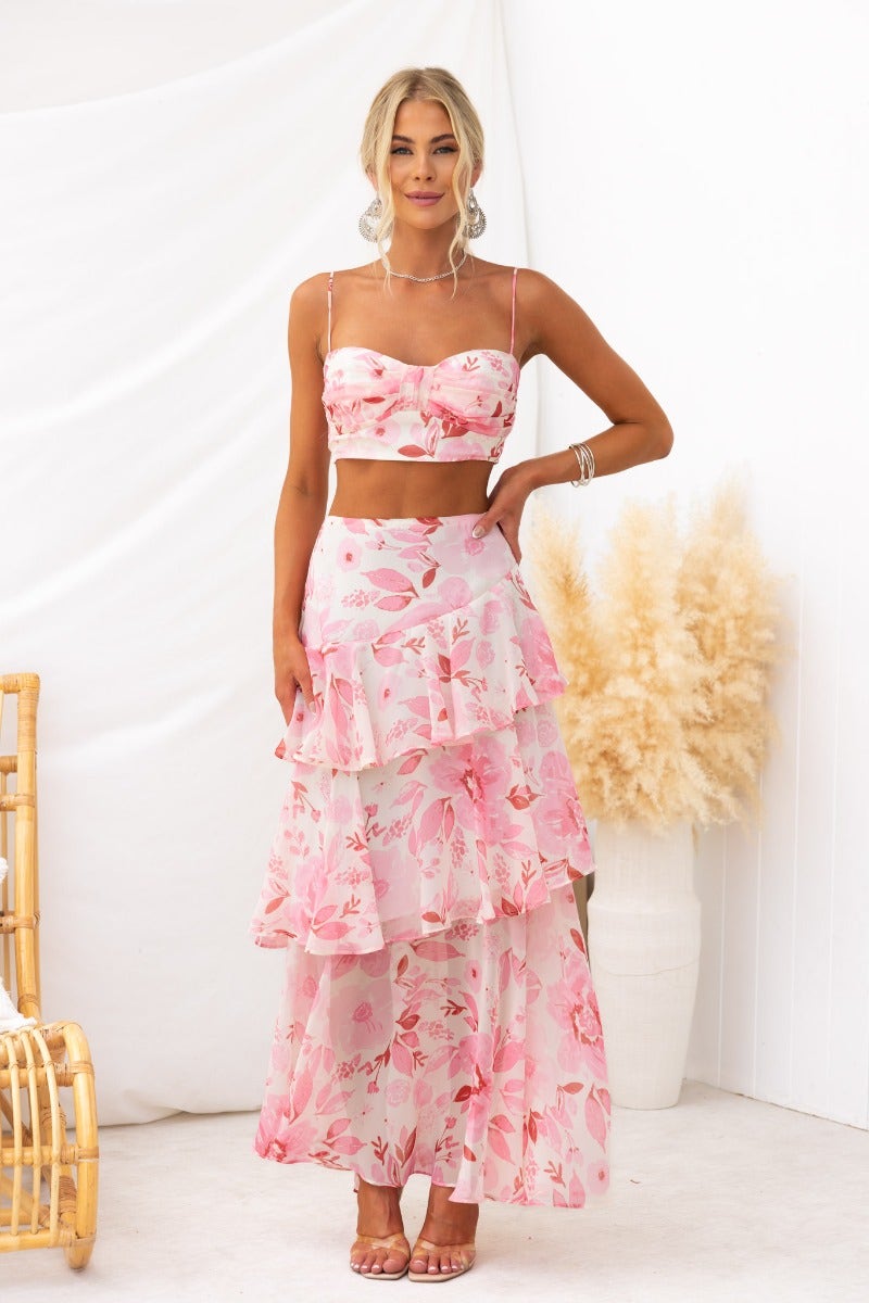 Model wearing Saphina Top with floral print, adjustable straps, and layered skirt in a pastel pink color.