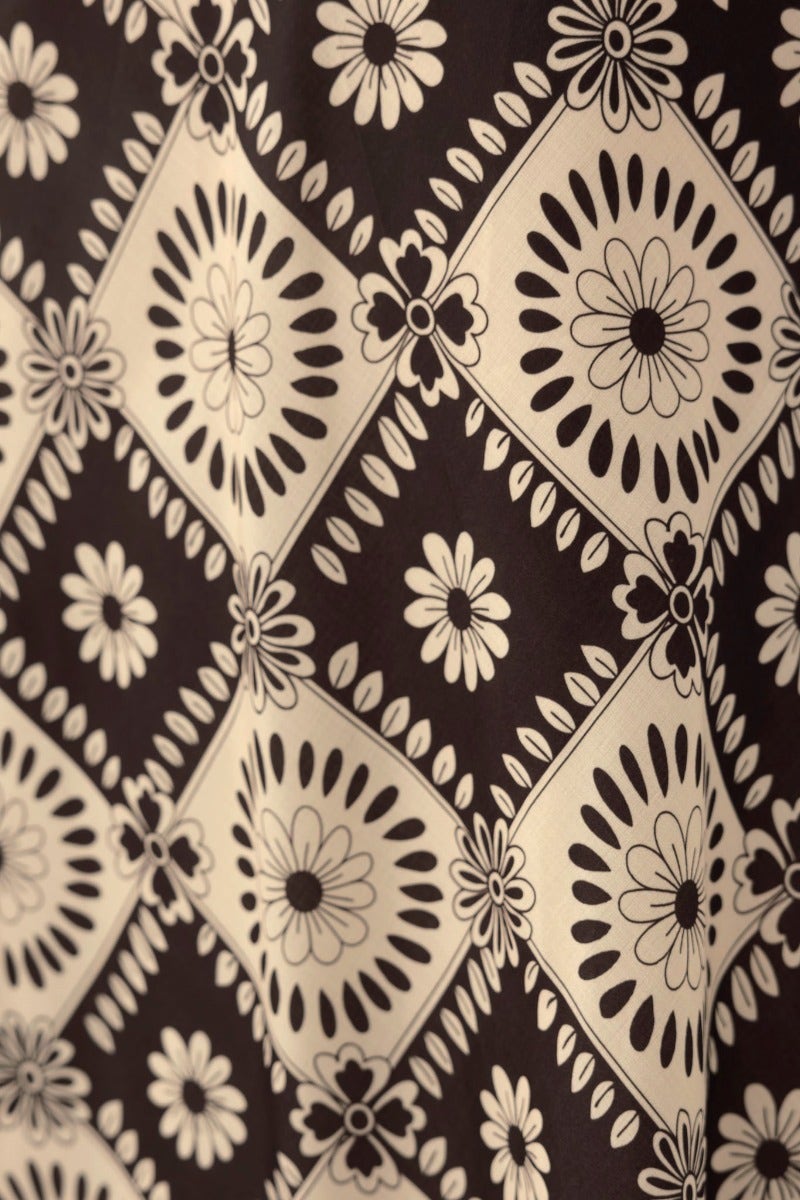 Floral print pattern featuring black and cream daisies on a soft fabric, perfect for a stylish top.