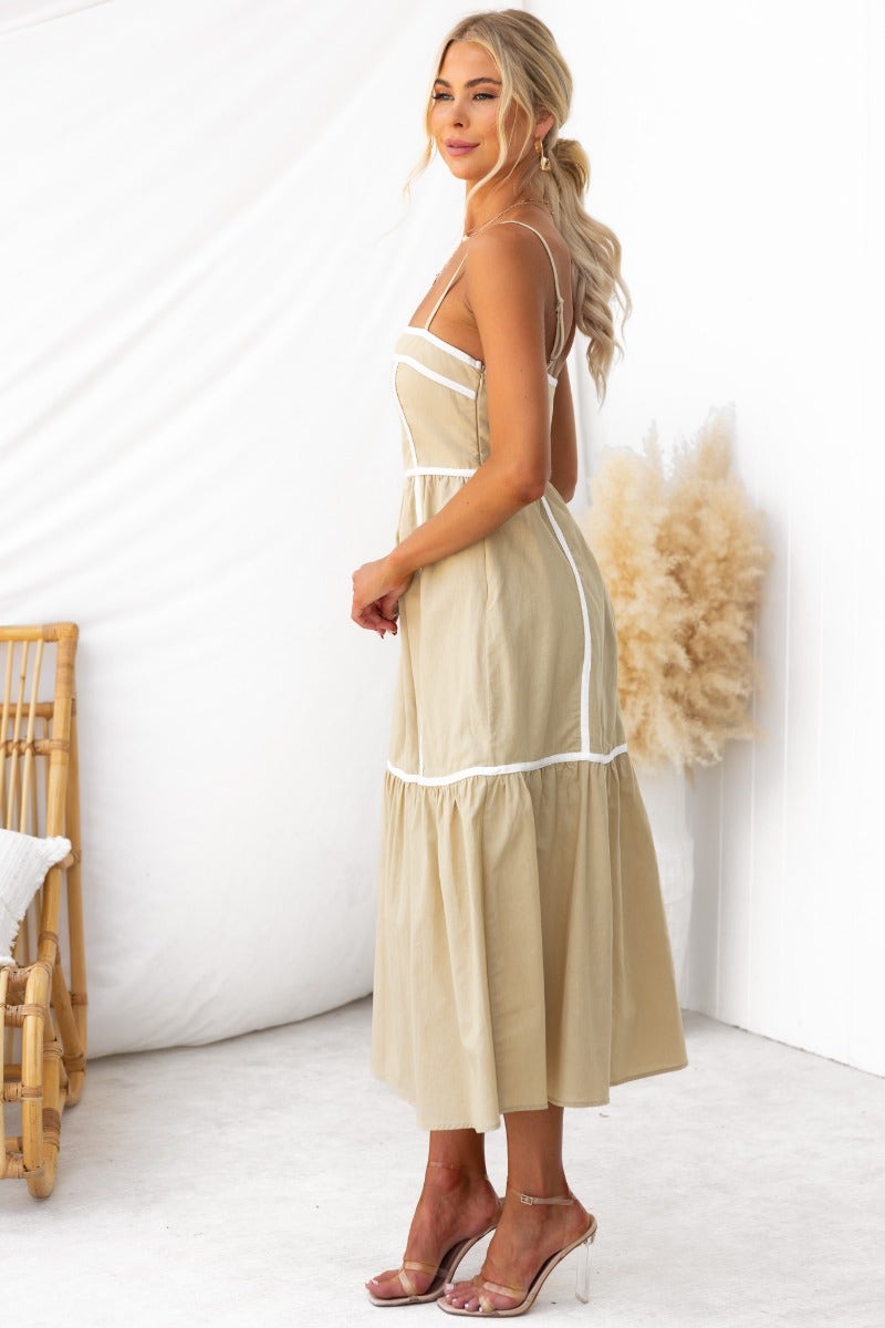 Cianna Midi Dress in light beige with adjustable straps and tiered hem, styled with clear heels on a model.