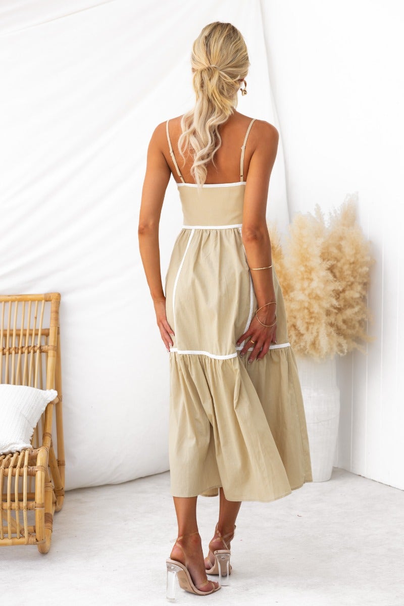 Back view of Cianna Midi Dress in beige, featuring adjustable straps and a tiered skirt, paired with heels.