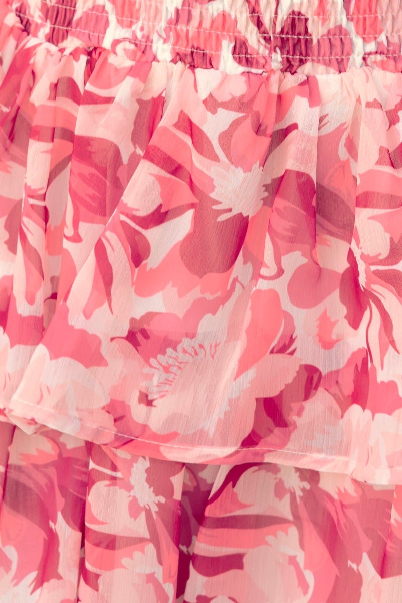 Close-up of a pink floral print chiffon dress with ruffled layers and elastic waist detailing.