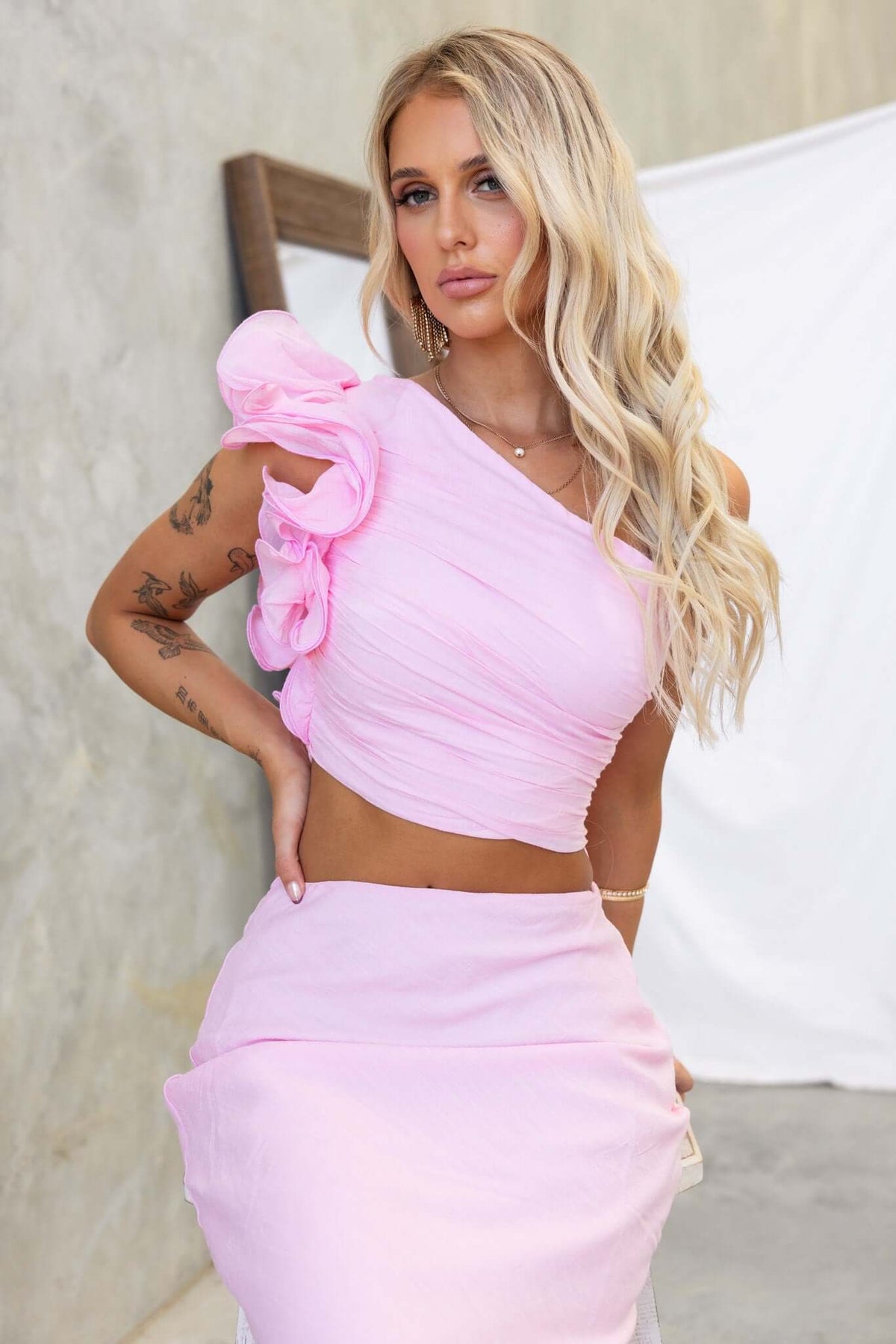 Model wearing pink Meriden Top with one-shoulder design, ruffle detail, and chiffon fabric.