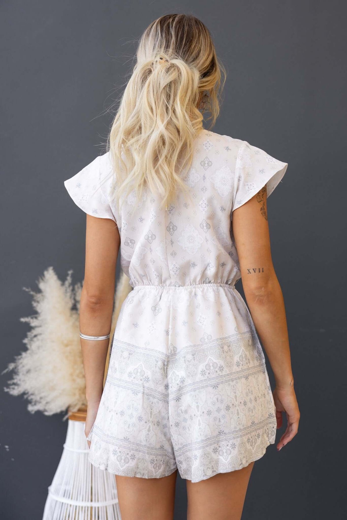 Back view of Kenny Playsuit with flutter sleeves and elastic waistband, featuring a linen look and styled with pockets.