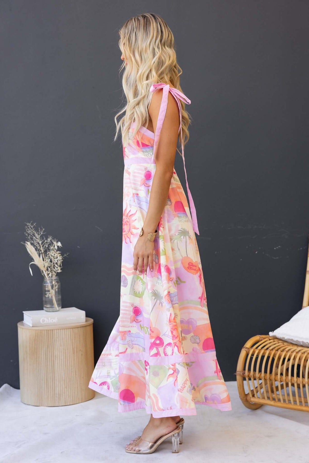 Model wearing Oreta Maxi Dress with square neckline and tie straps, featuring floral print and a flowing silhouette.