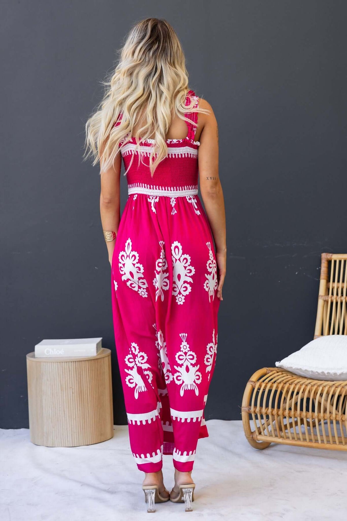Back view of a woman in a vibrant pink Summer Fields Maxi Dress with white floral design, showcasing a stylish summer look.