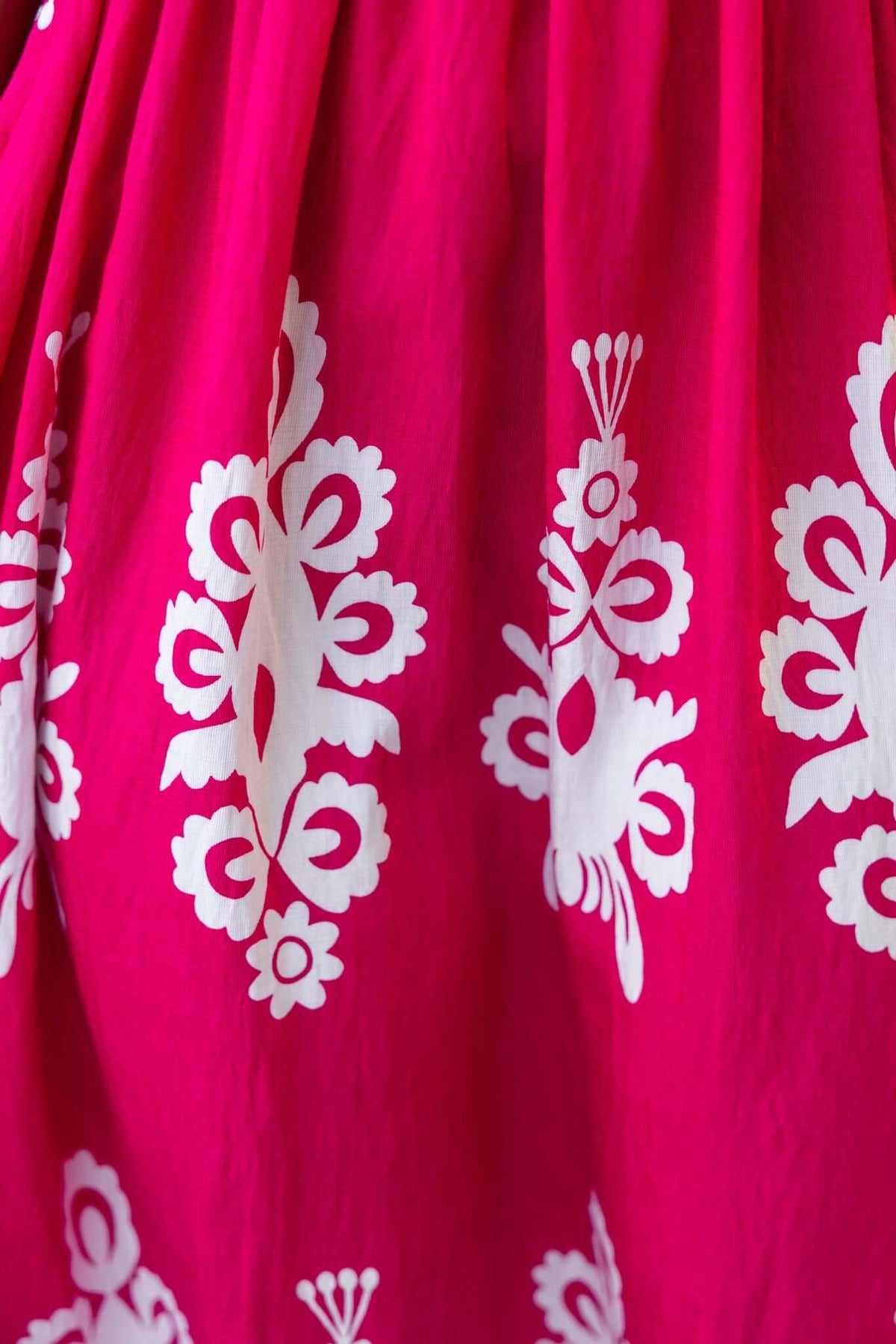 Close-up of vibrant pink fabric with white floral patterns, ideal for a summer maxi dress.