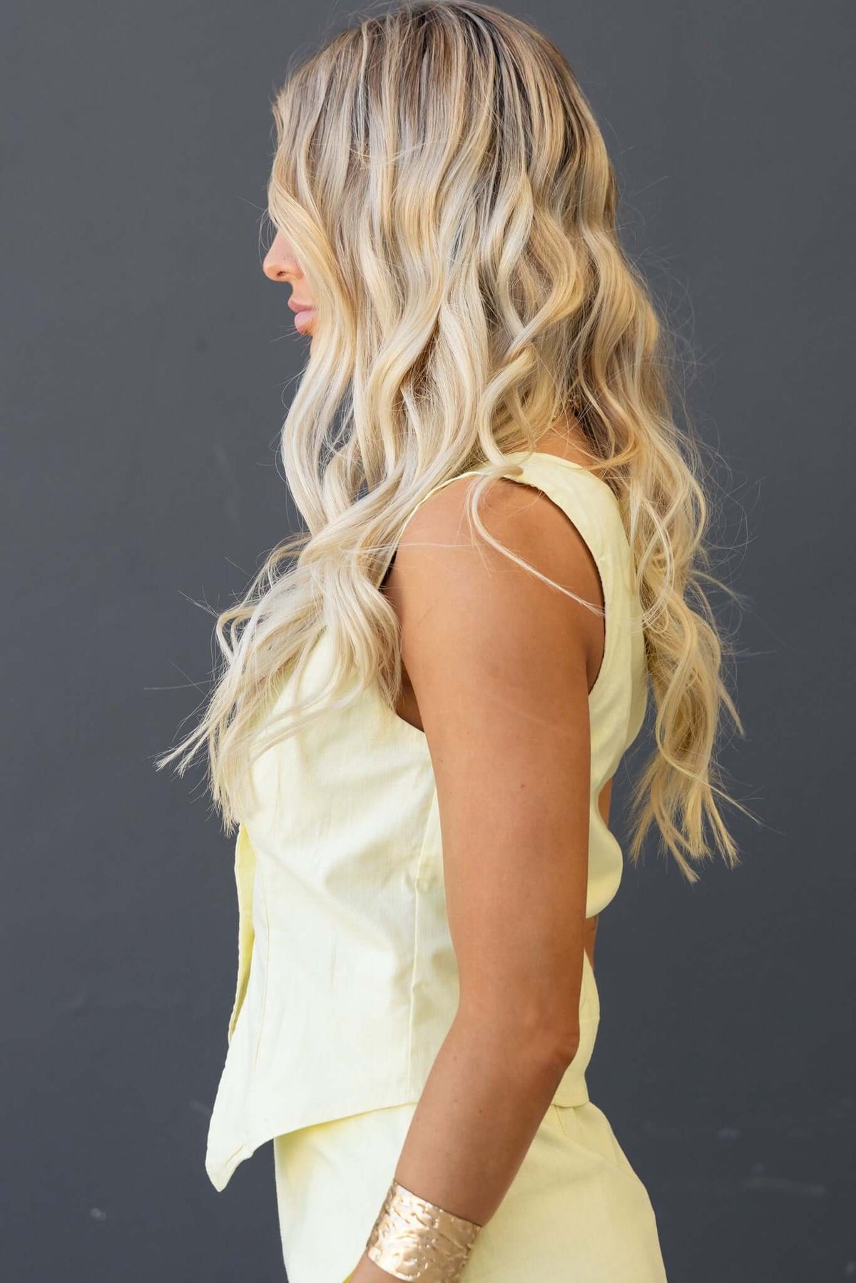 Pamela Top in light yellow, featuring a button-up front, styled with wavy hair and a modern fit.