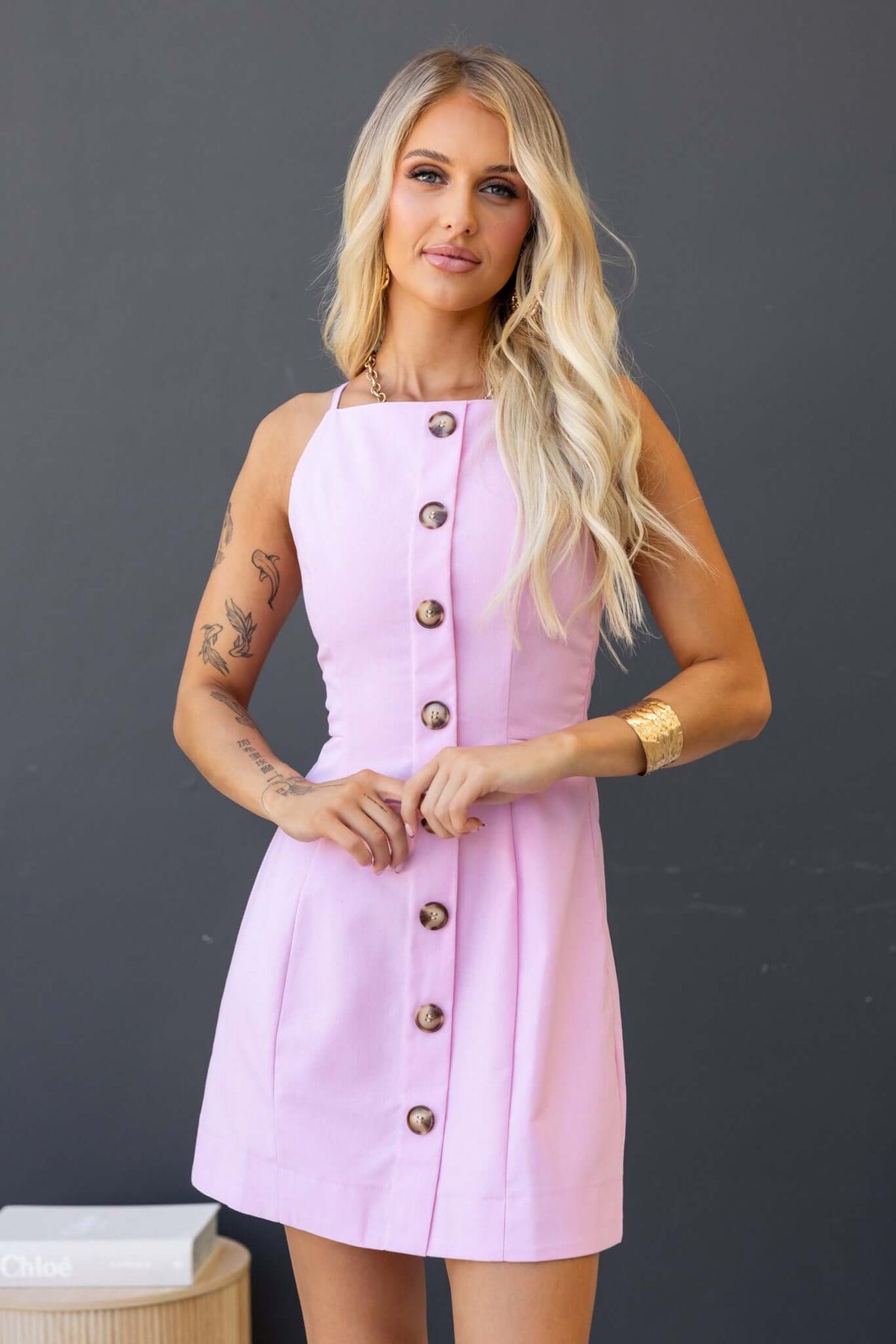 Model wearing the Olean Dress in pastel pink with faux buttons and invisible side zip, showcasing a casual summer look.