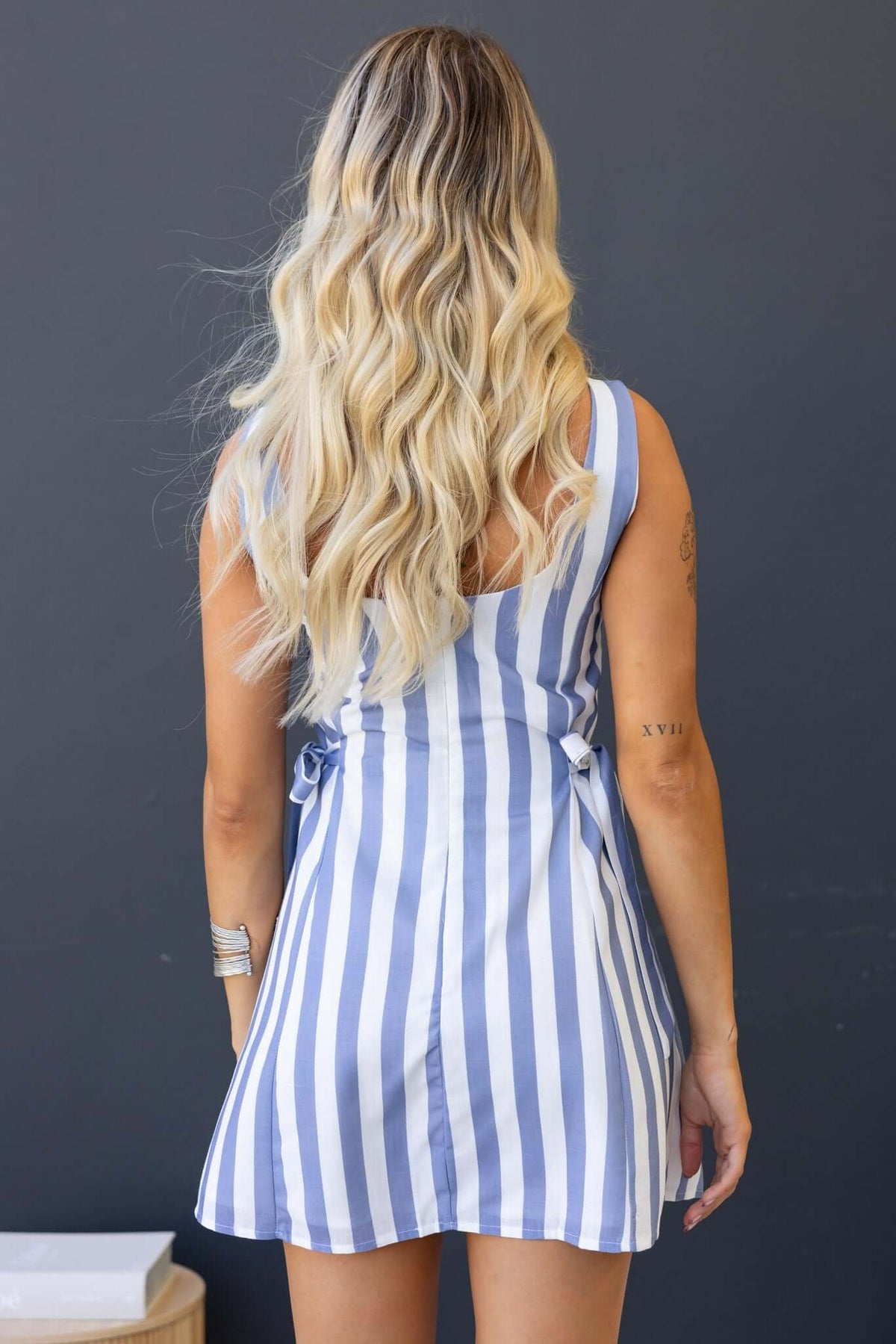 View of the back of the Cartwright Dress featuring a low-cut back and tie details, styled with vertical stripes.