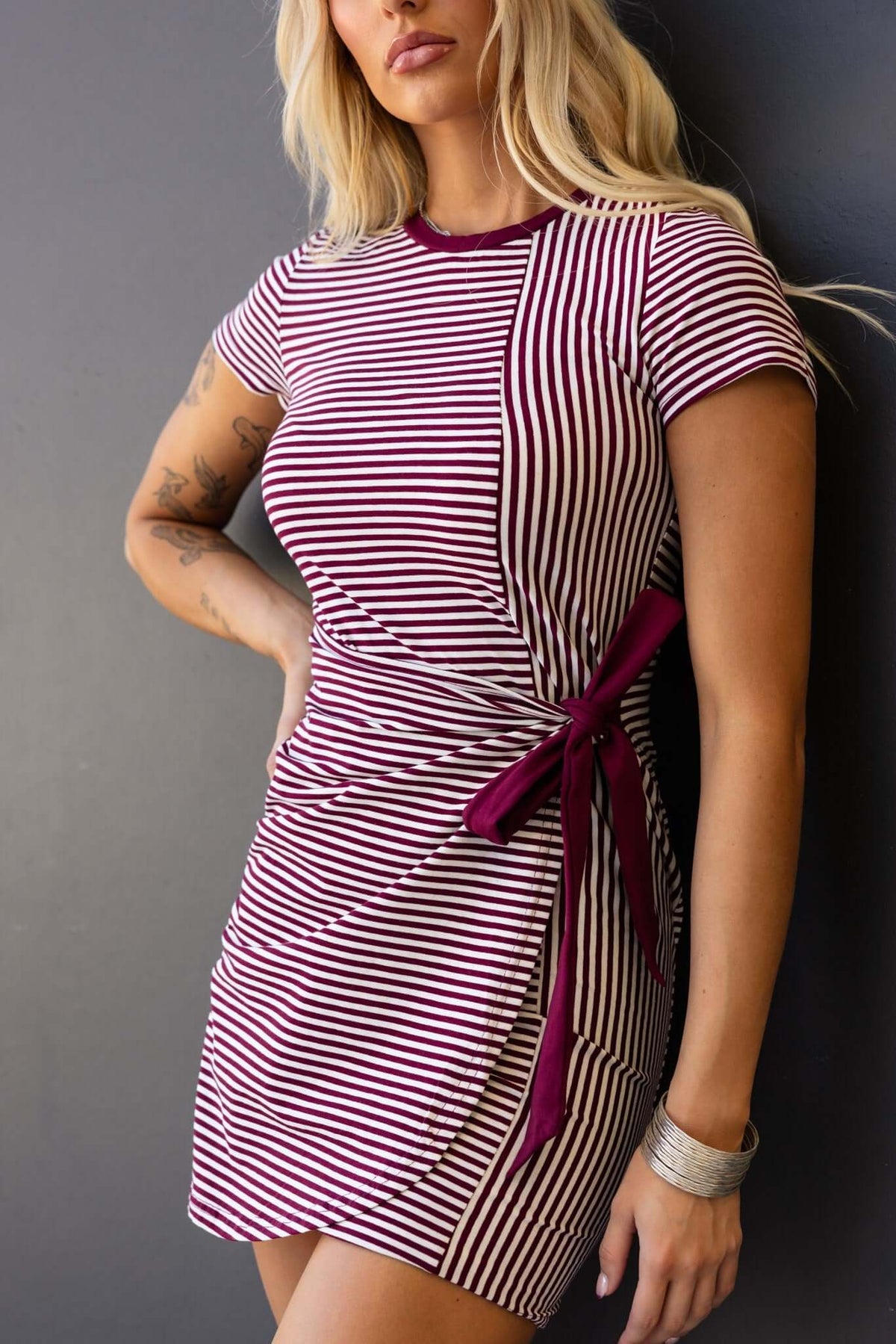 Gozoa dress featuring a round neckline, wrap-look tie, and stylish striped design in burgundy and cream.