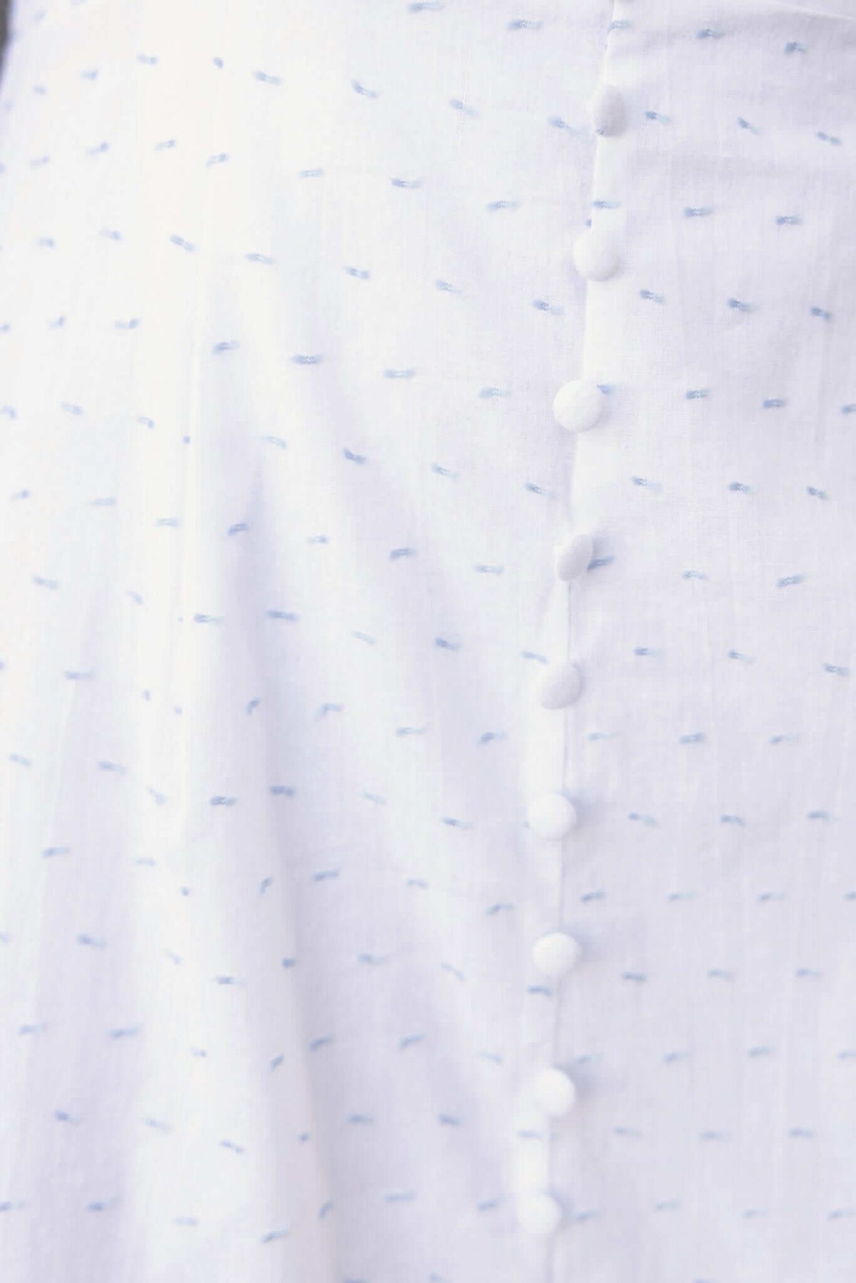 Close-up of Harp Dress showing off-shoulder design and faux buttons on a lightweight cotton fabric.