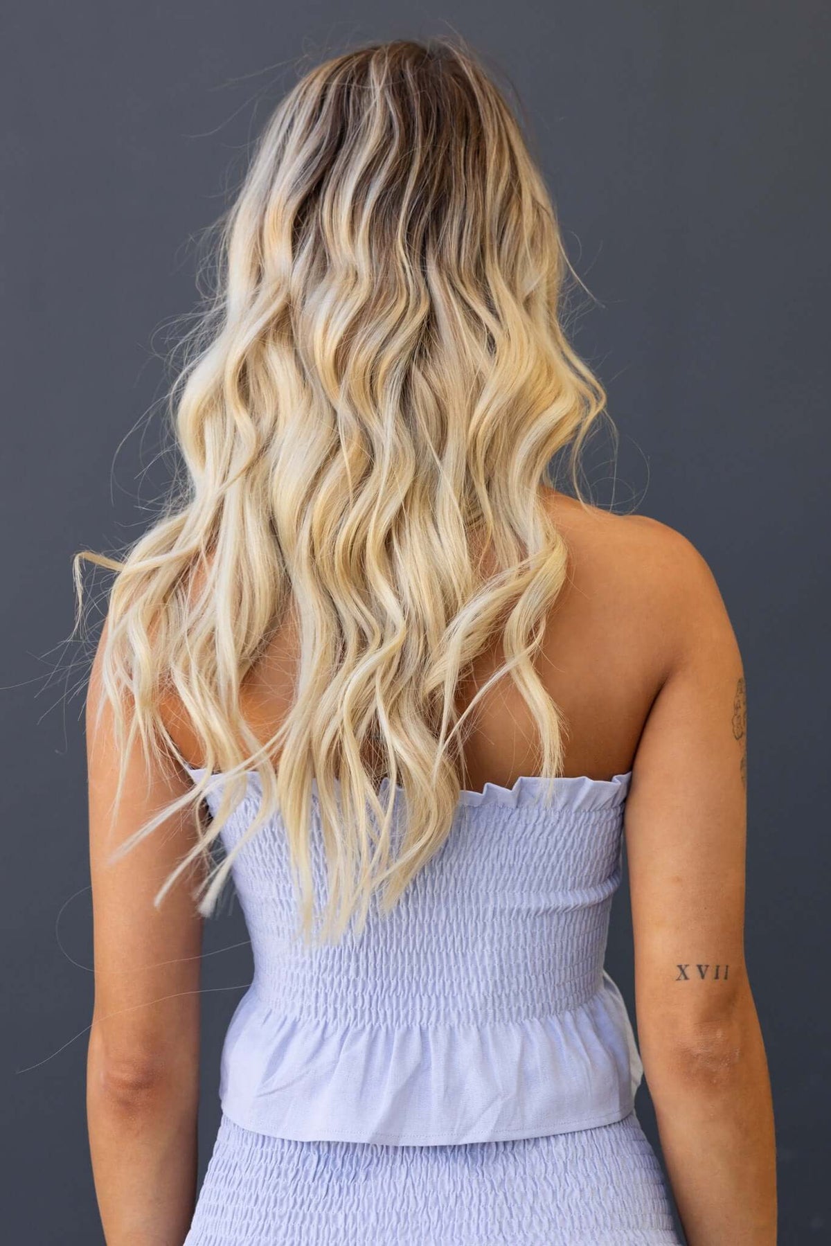 Back view of a woman wearing the Nolan Top, featuring an elastic bodice and light blue fabric with a relaxed fit.