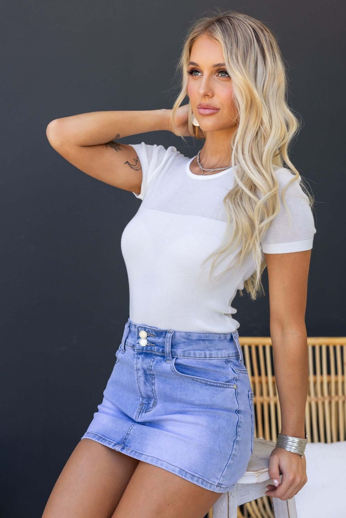 Model wearing the Topaz Tee with sheer panel, styled with a denim skirt, showcasing a casual summer outfit.