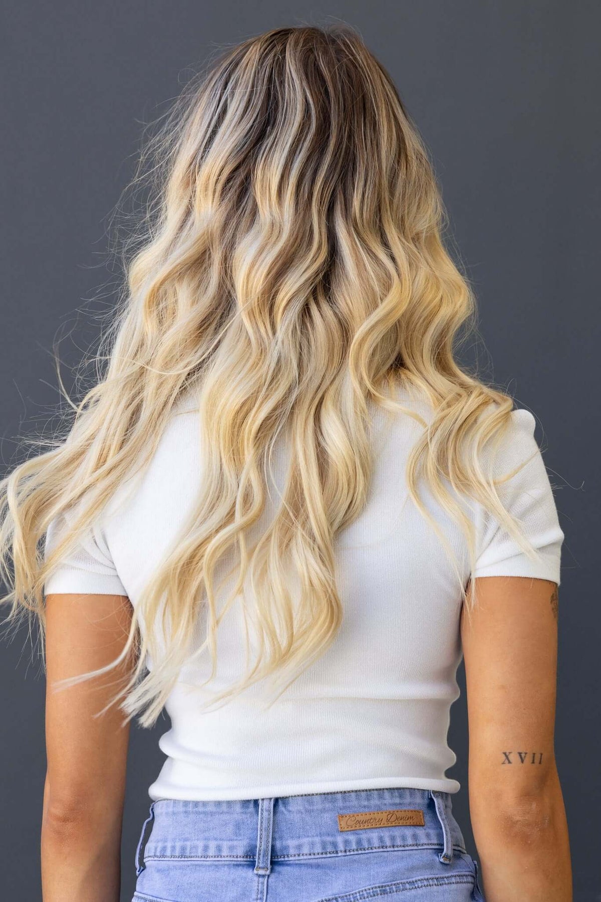 Back view of a model wearing the Topaz Tee, showcasing its round neckline and wavy hair, paired with light wash jeans.