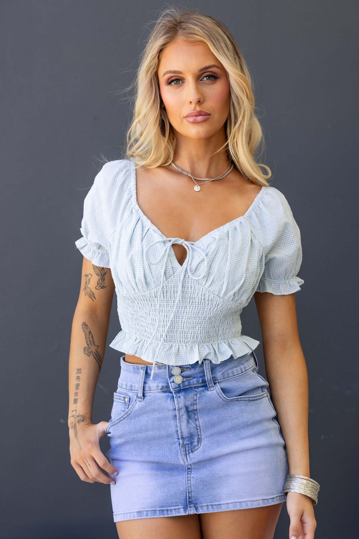 Sonnie Top in light blue with tie at bust, elastic fit, paired with denim skirt, model showcasing stylish summer outfit.