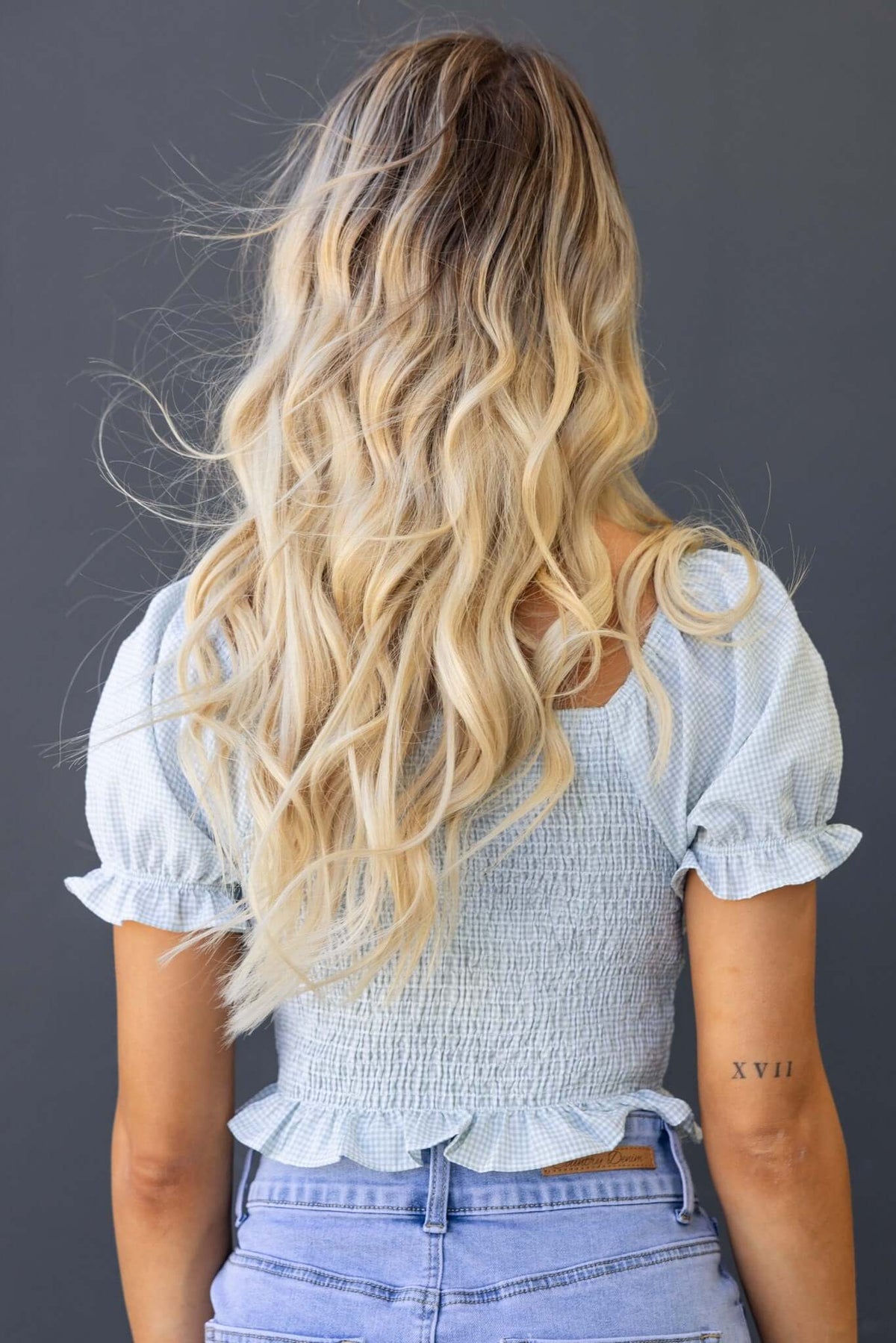 Back view of a woman in a blue tie bust Sonnie Top with elastic throughout and puff sleeves.