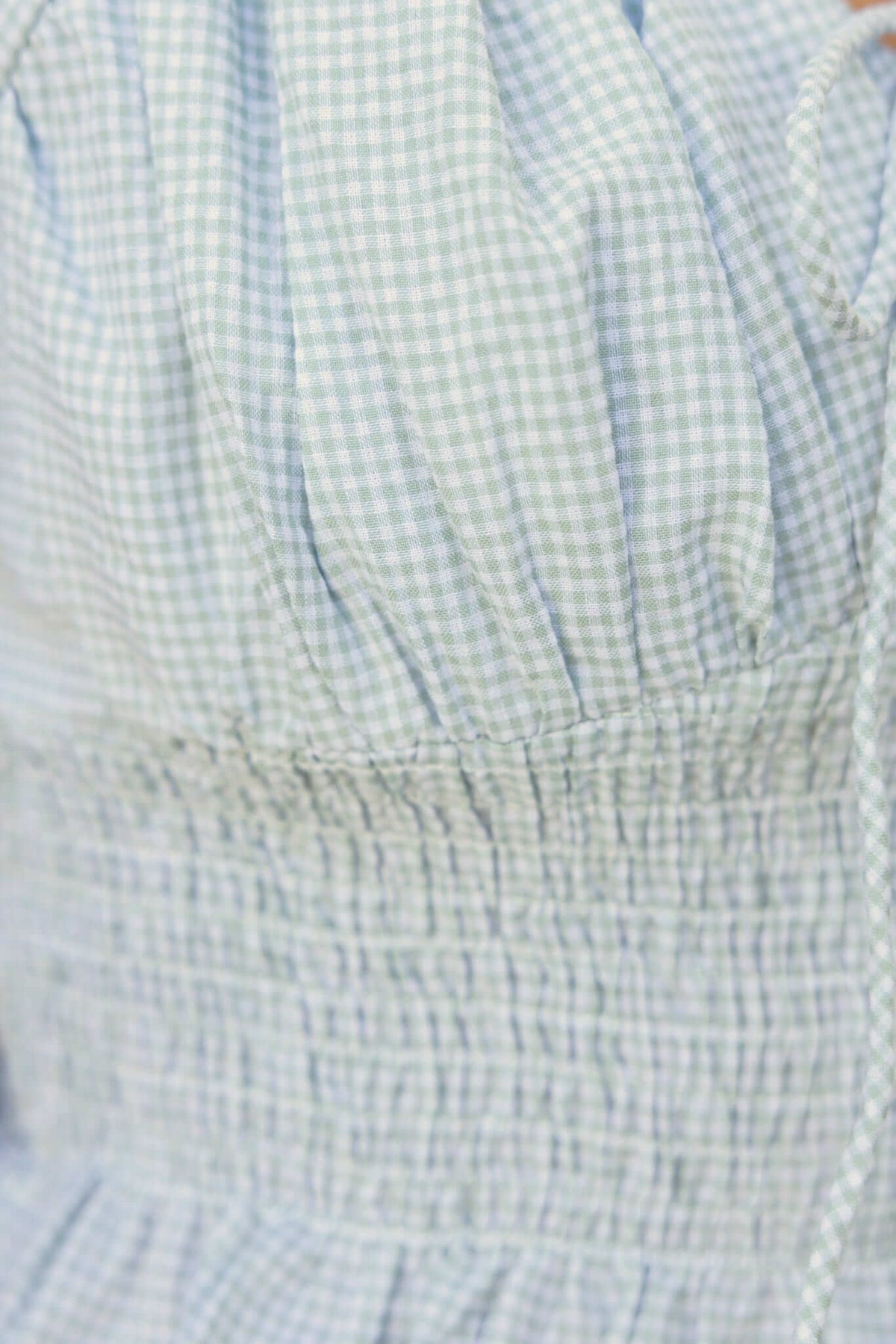 Close-up of the Sonnie Top featuring a checkered pattern, elastic band, and tie detail at the bust.
