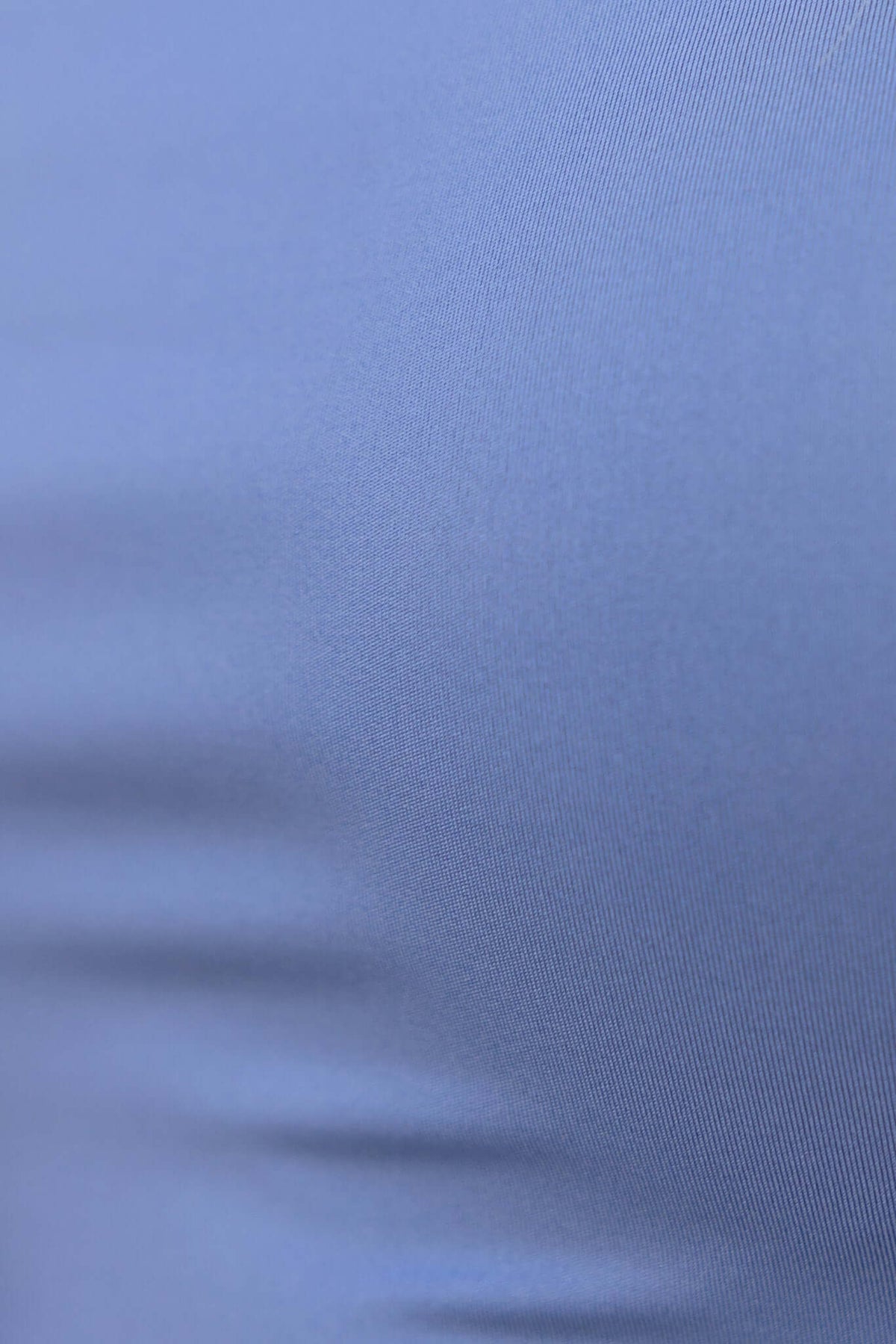 Close-up of smooth, stretchy blue fabric used in the Paria Bodysuit, showcasing its quality material and texture.
