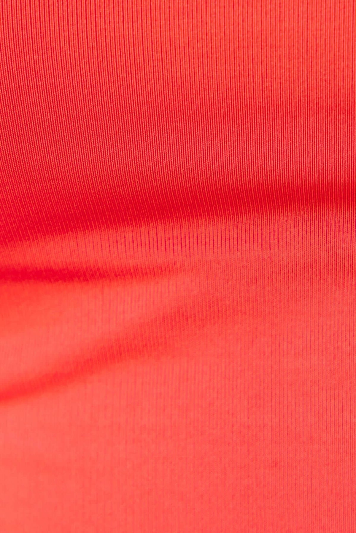 Close-up of ruby bodysuit fabric showcasing soft stretch material in vibrant red color.