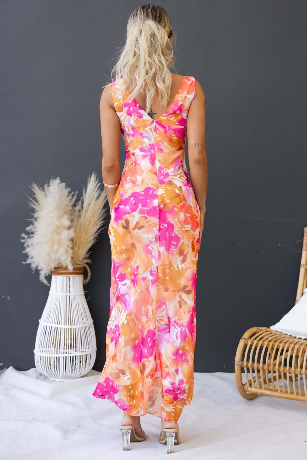 Stylish woman in a colorful floral Qilax maxi dress, showcasing the back view and elegant design.
