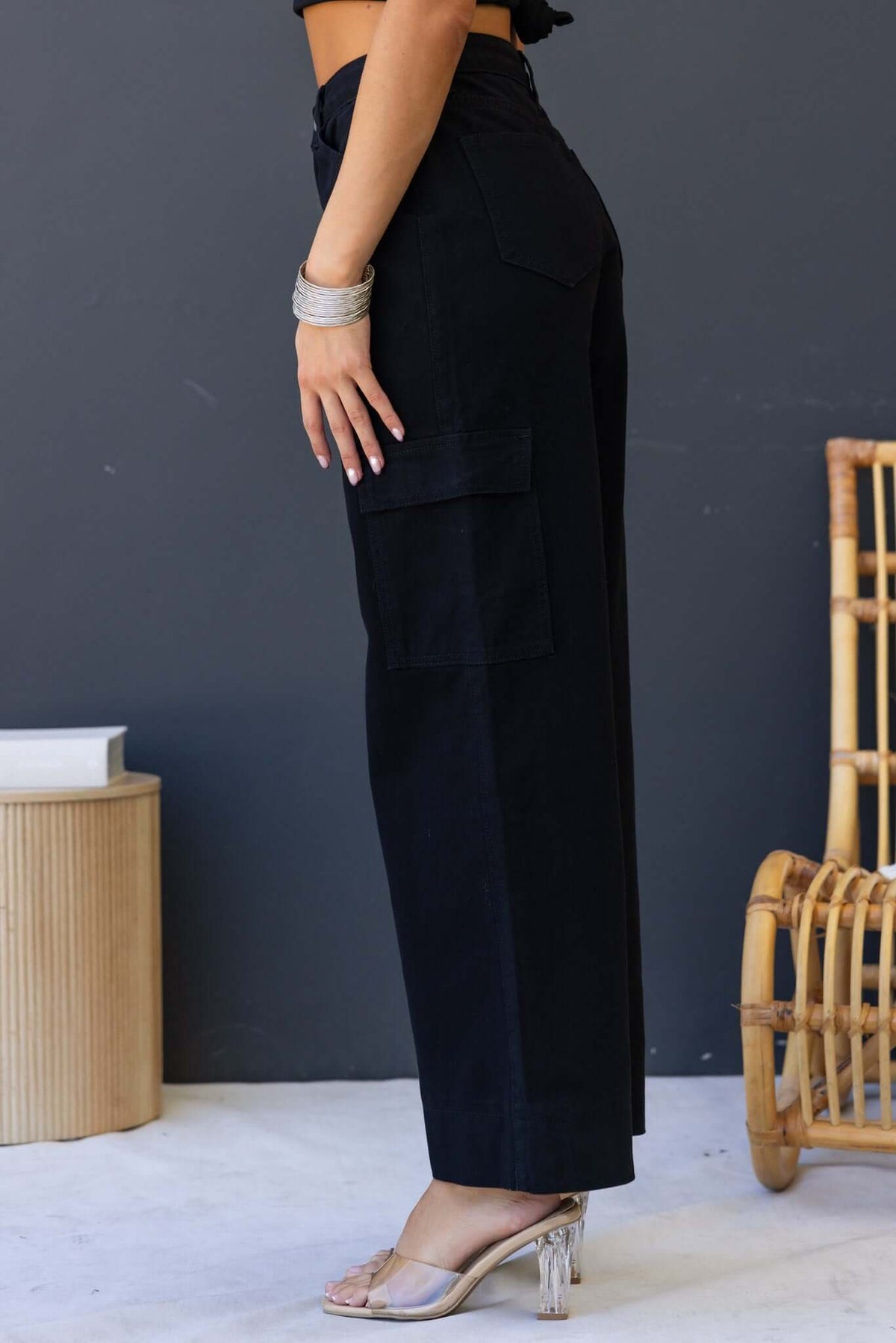 Side view of Chandler black denim cargo jeans with oversized legs and pockets, styled with a crop top.