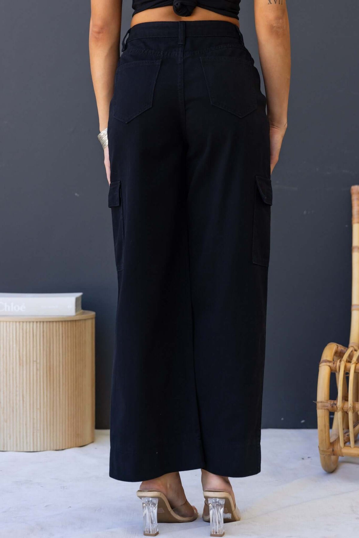 Back view of black cargo jeans with wide legs, mid-high waist, and multiple pockets, styled casually.