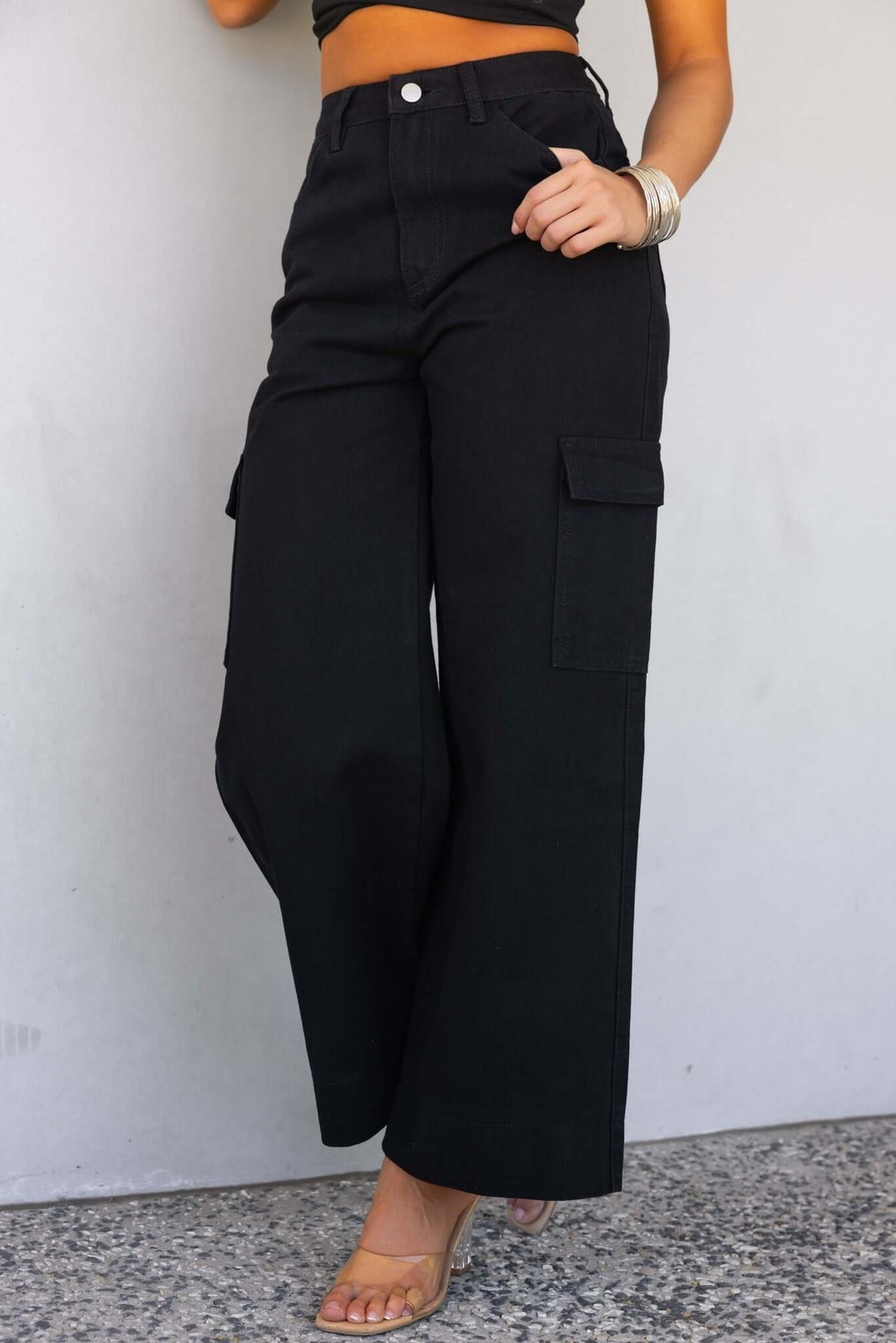 Black cargo denim jeans with wide legs and mid-high waist, featuring multiple pockets.